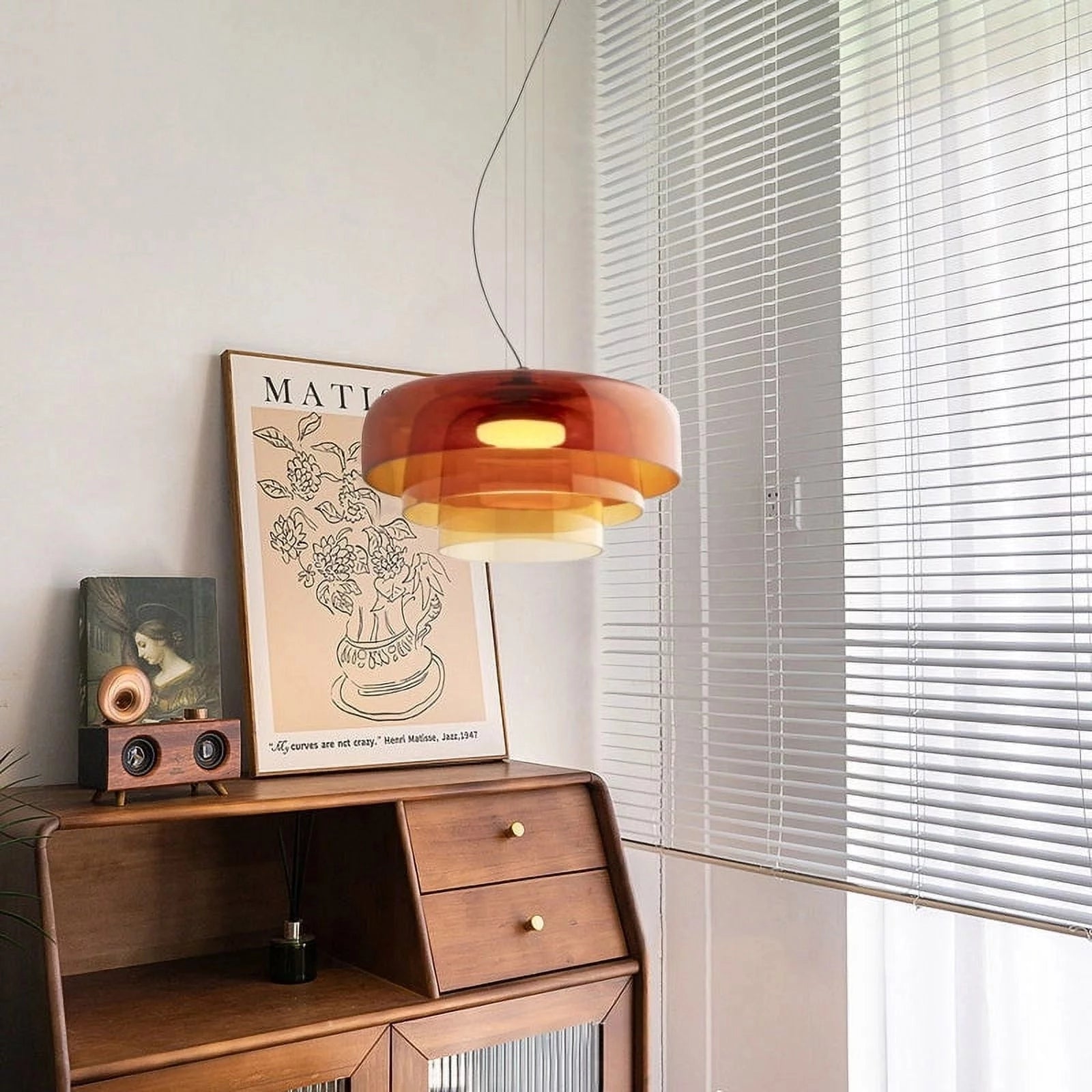 Modern multi-colored glass pendant light hanging in a contemporary interior with wooden cabinetry and orange accents.