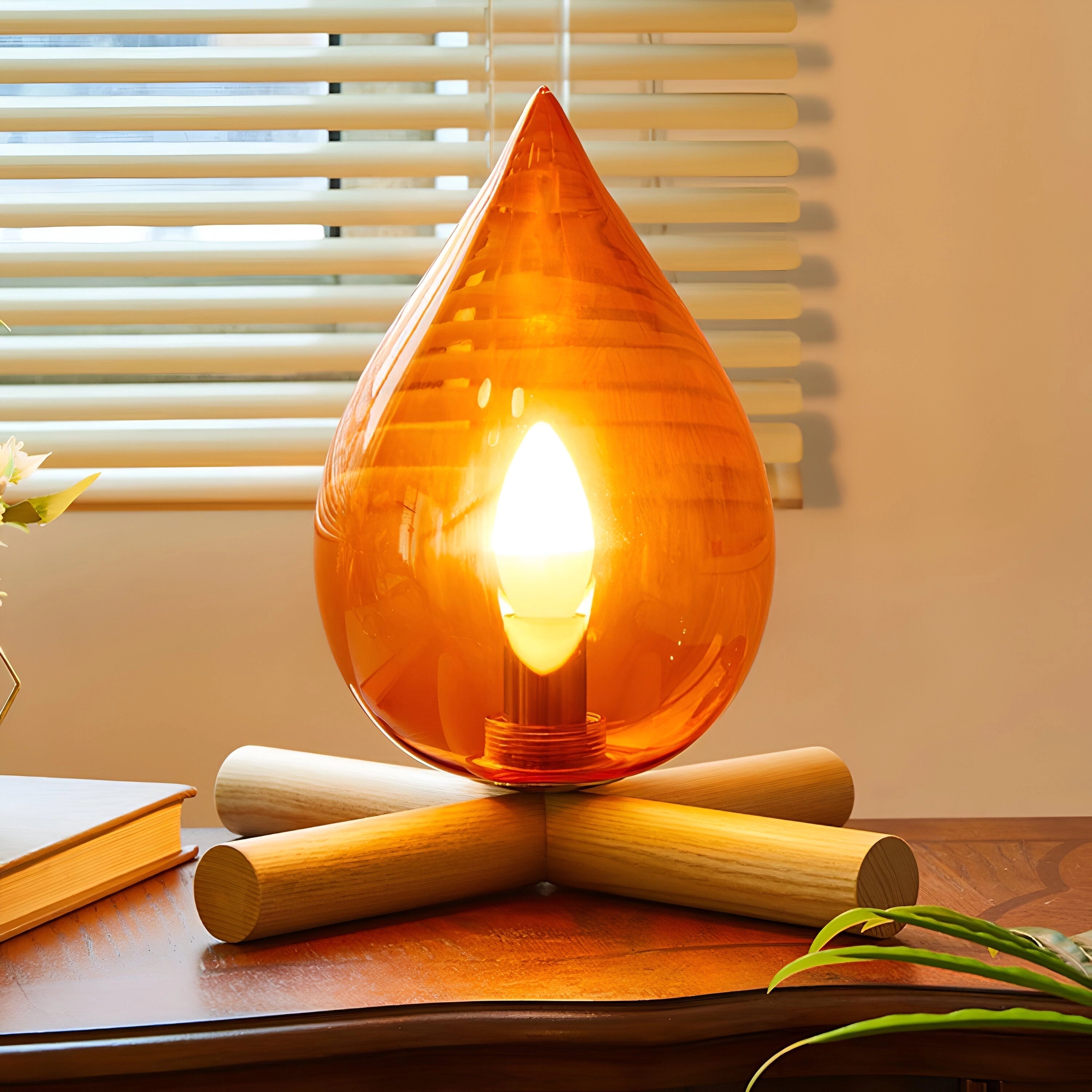 Modern orange glass table lamp with a flame-like artistic design, featuring an amber hue and wooden base, emitting warm light.