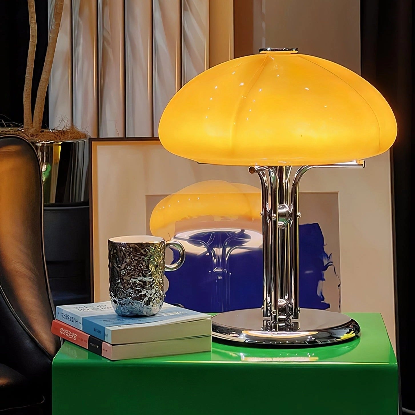 Modern orange globe table lamp with chrome base, emitting warm light, placed on a table in a stylishly decorated room.