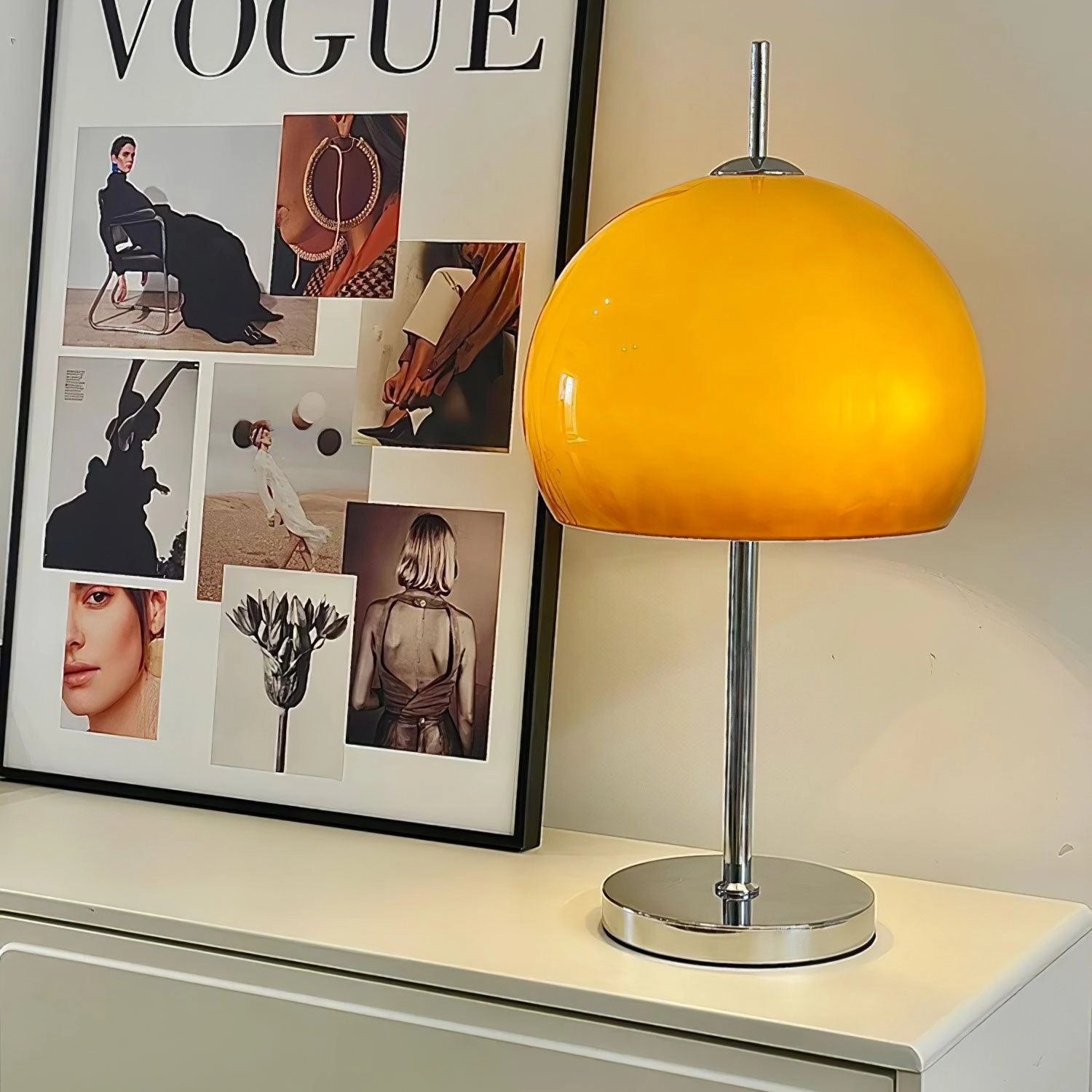 Modern orange globe table lamp with chrome base and warm light, positioned on a table, with decorative elements.
