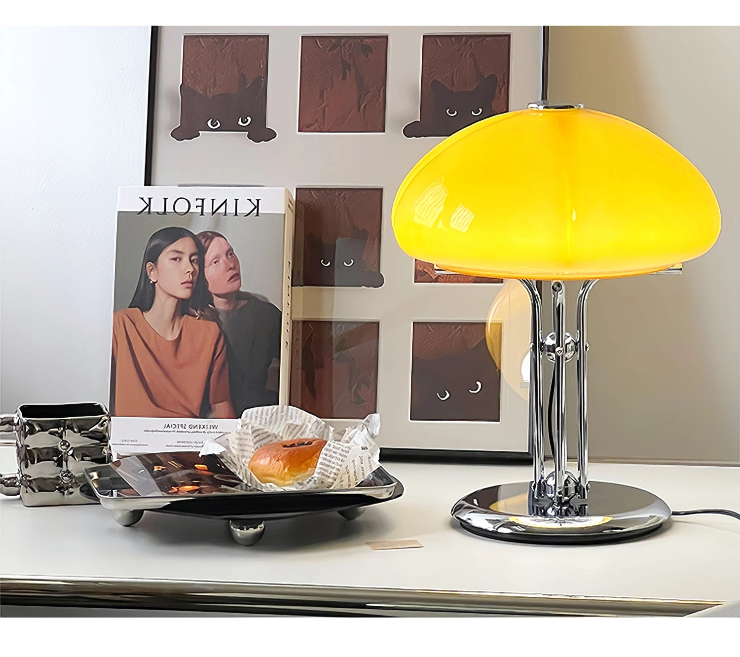Modern orange globe table lamp with chrome base, emitting warm light, placed on a table.