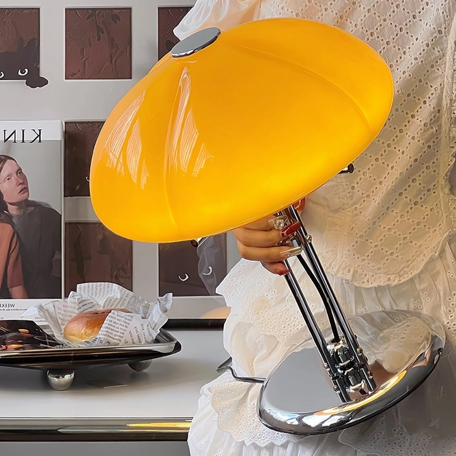 Modern orange globe table lamp with chrome base emitting warm light, placed on a table.