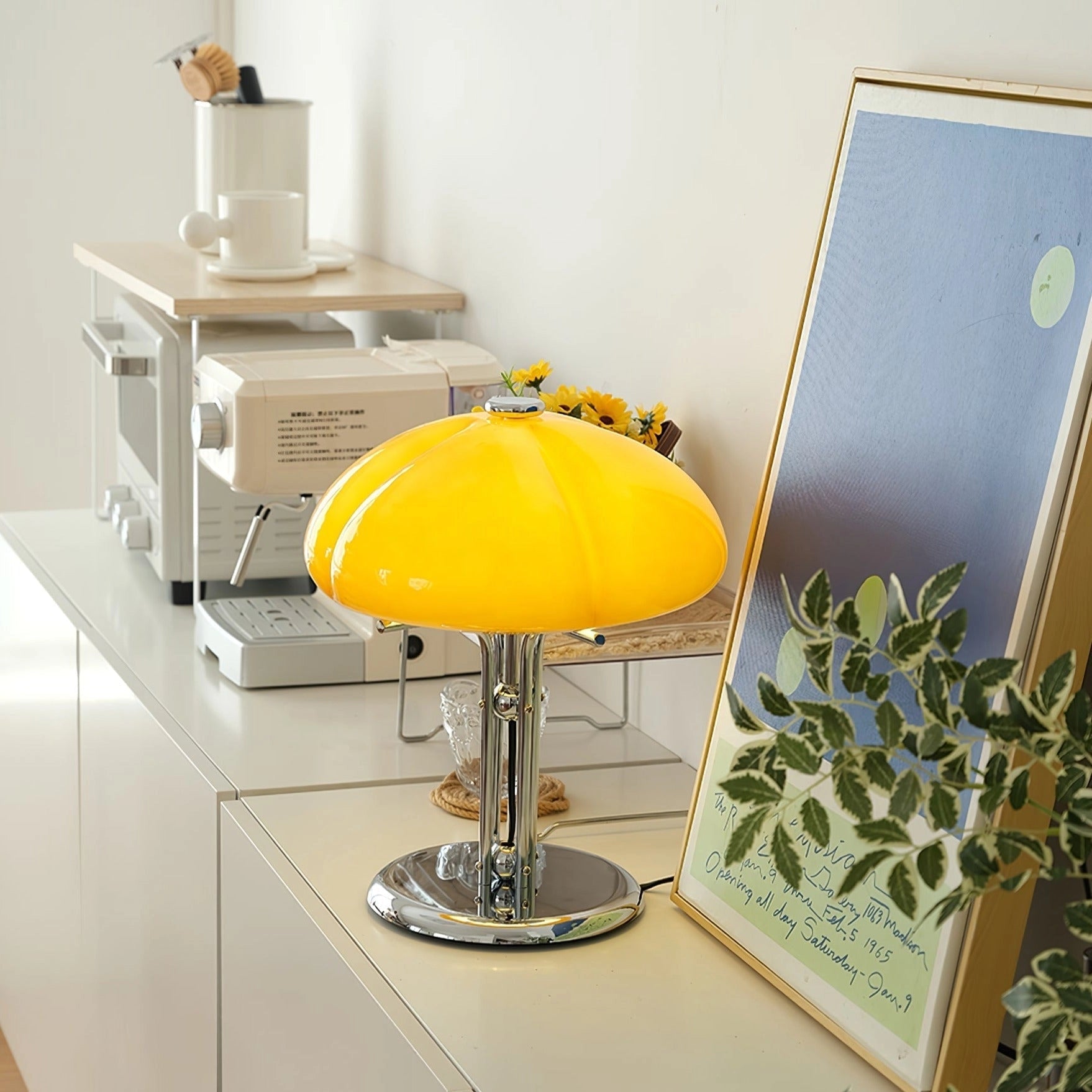 Modern orange globe table lamp with chrome base emitting warm light, placed on a table with chair and plant nearby.