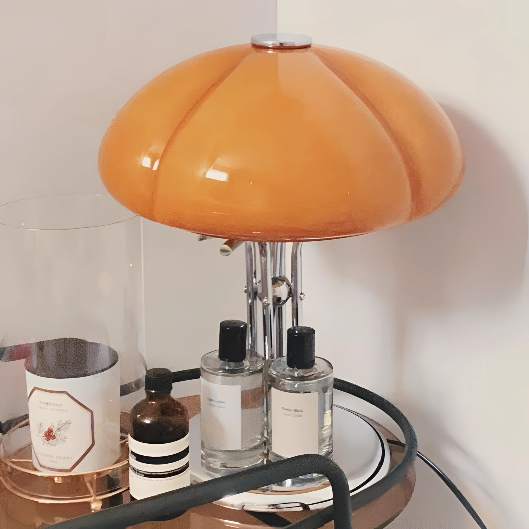 Modern orange globe table lamp with chrome base emitting warm light, placed on a wooden table.