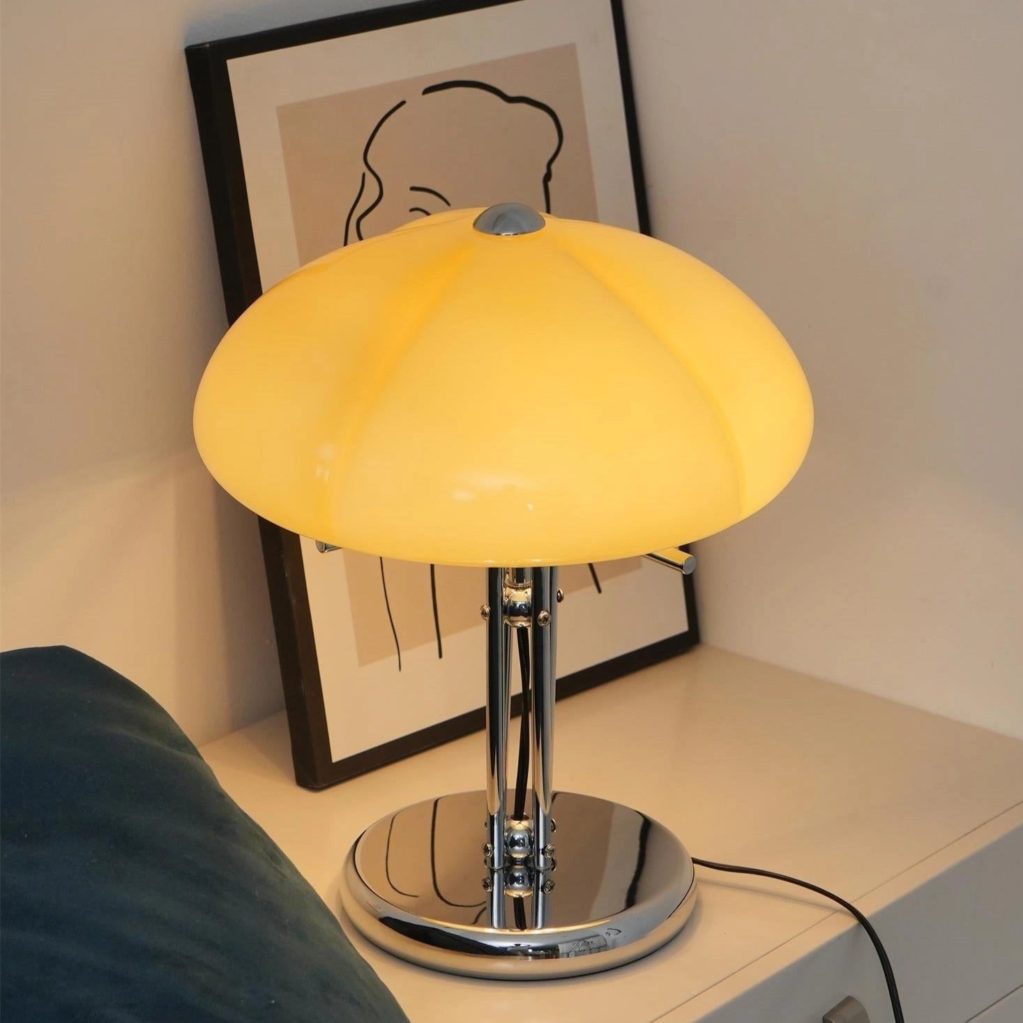 Modern orange globe table lamp with chrome base, warm light, and decorative elements, placed on a wooden table.