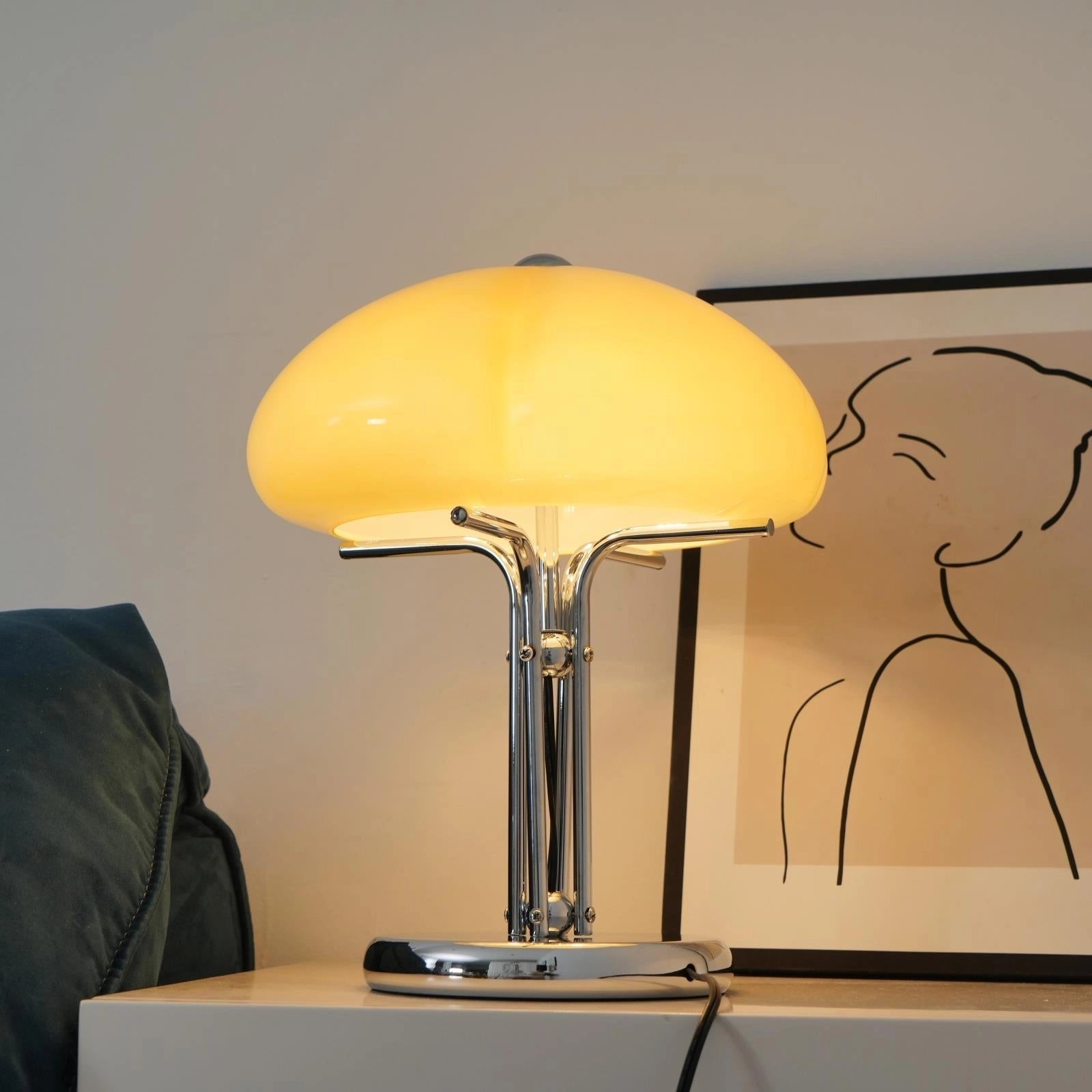 Modern orange globe table lamp with chrome base, emitting warm decorative light, placed on a wooden table.