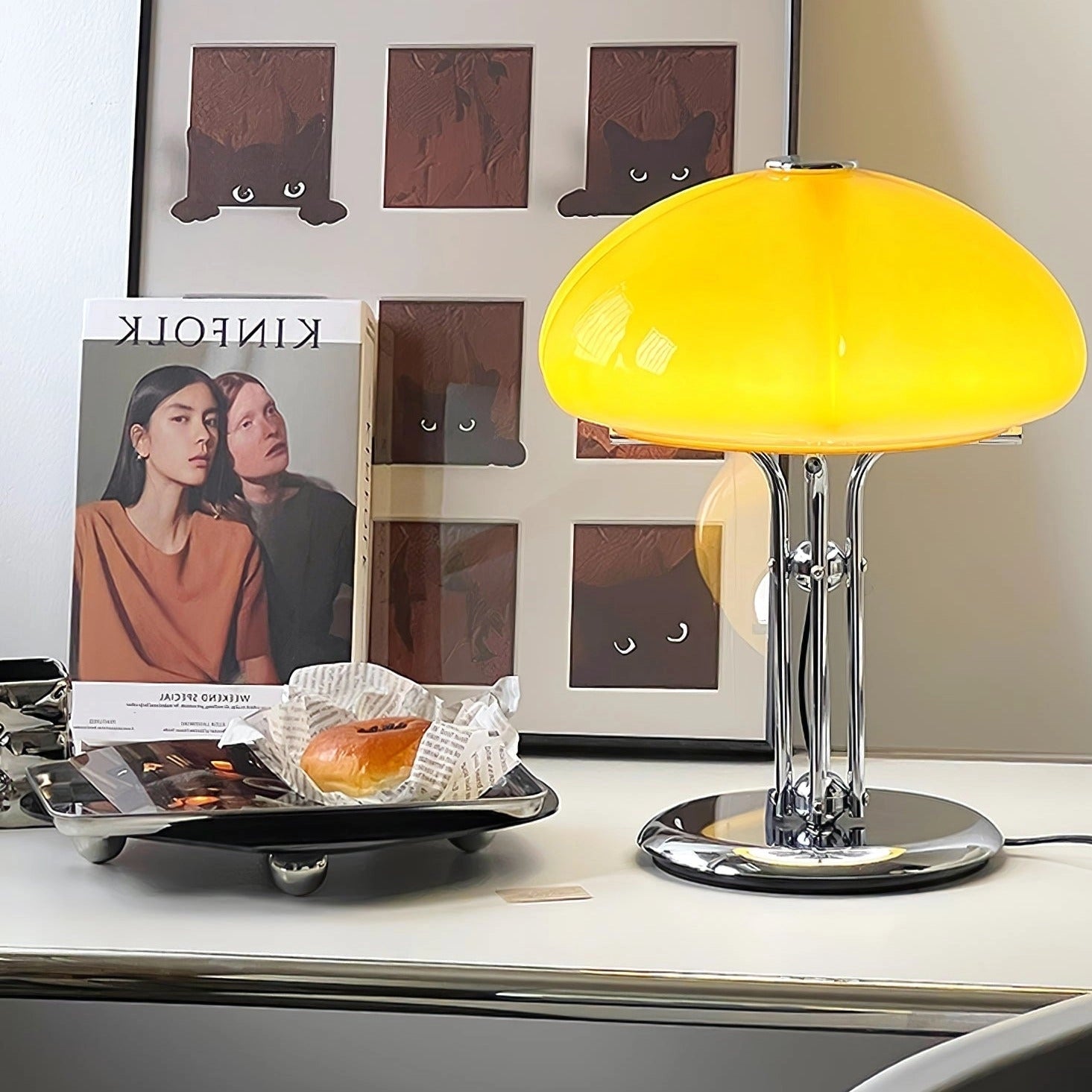 Modern orange globe table lamp with chrome base emitting warm light, placed on a table.