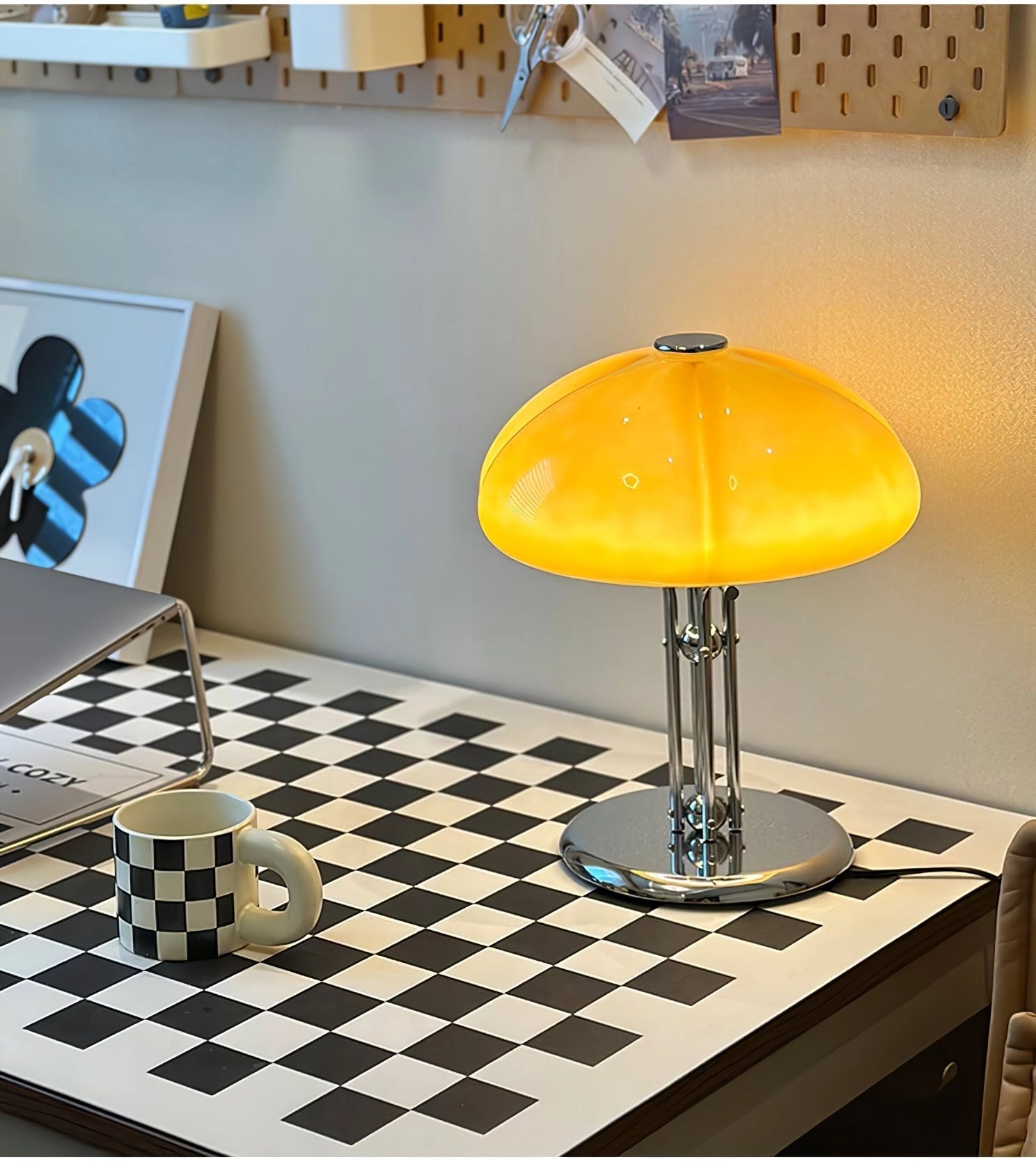 Modern orange globe table lamp with a chrome base, emitting warm light, placed on a wooden table in an interior setting.