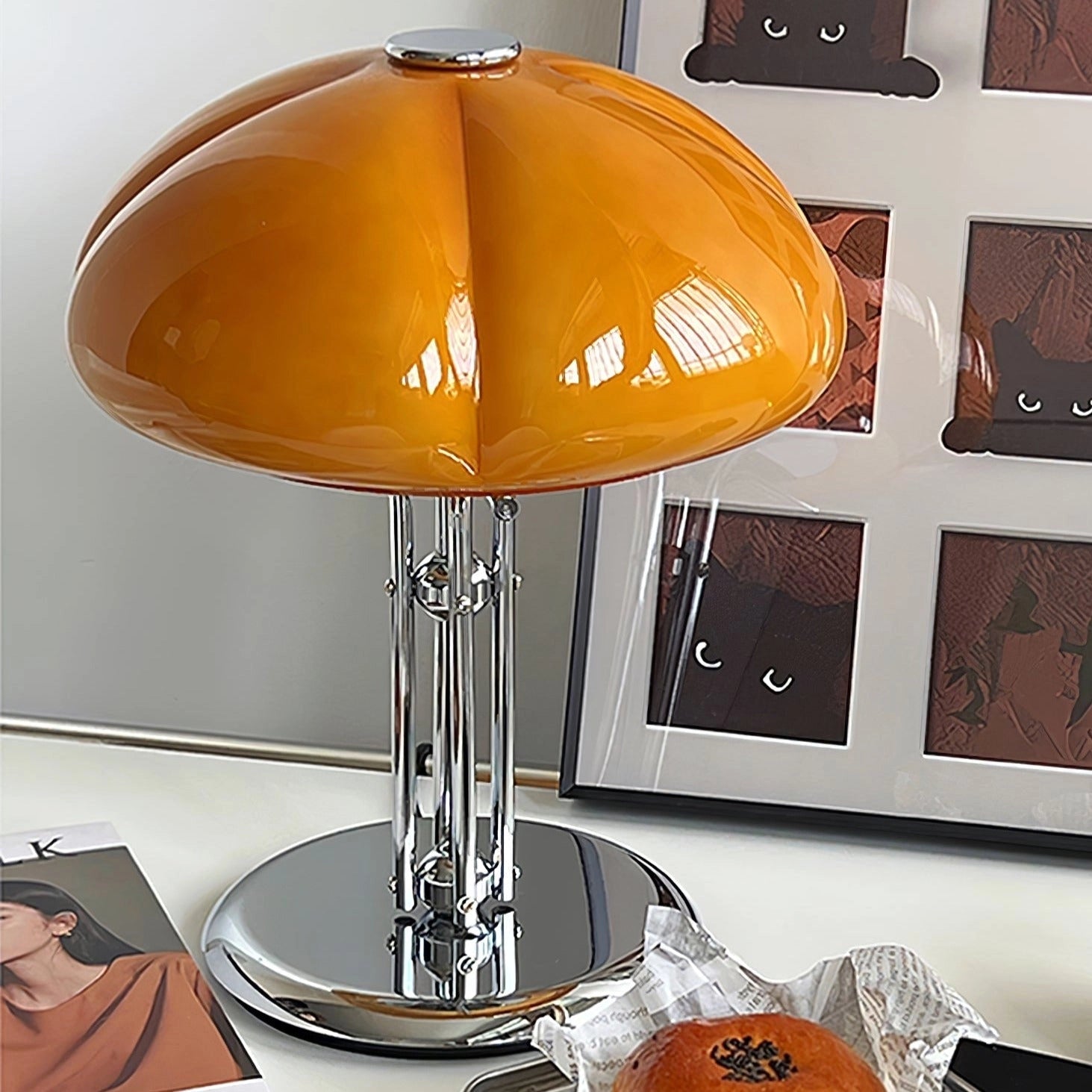 Modern orange globe table lamp with chrome base, emitting warm amber light; perfect for interior design and decoration.