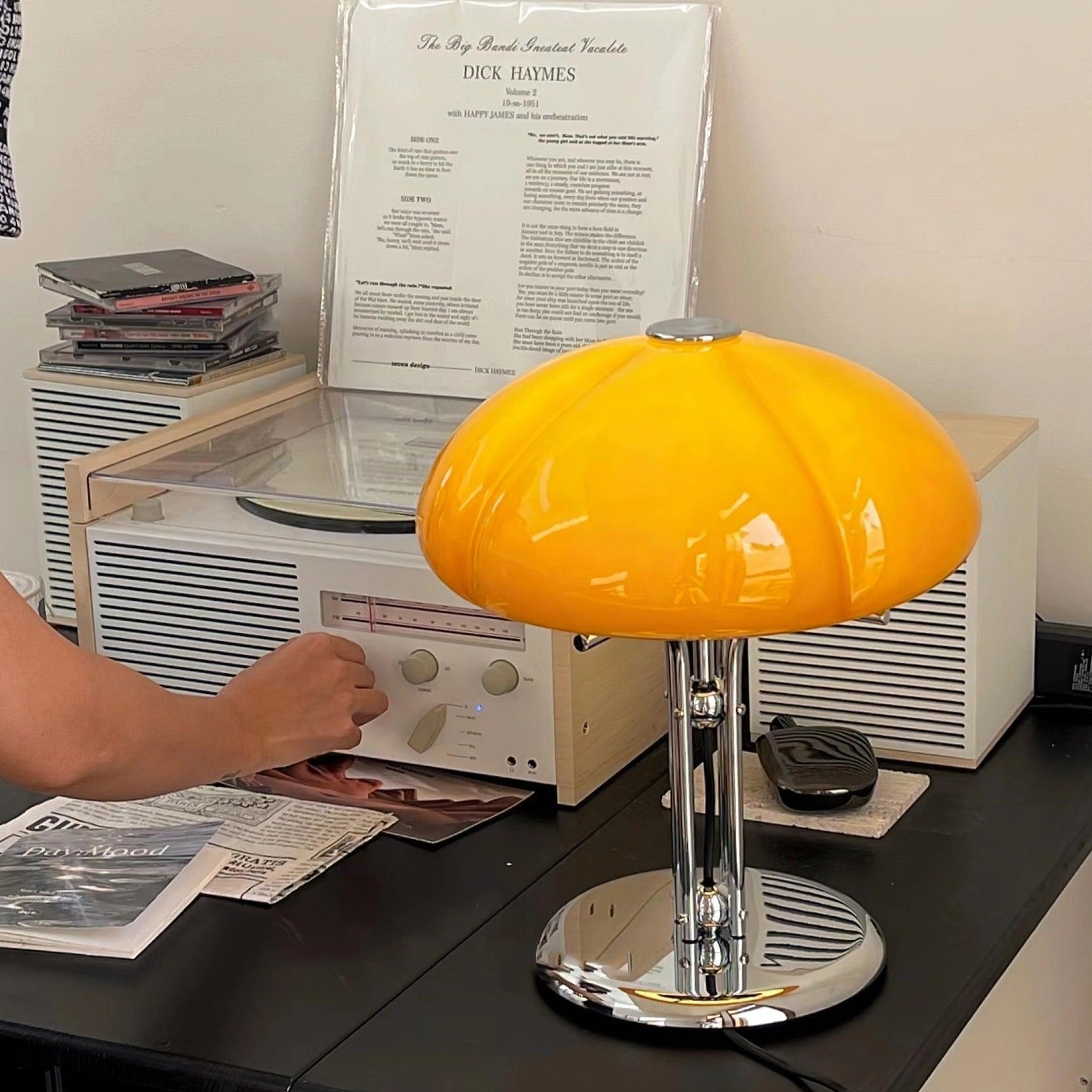 Modern orange globe table lamp with chrome base, emitting warm light, on a table in a contemporary room.