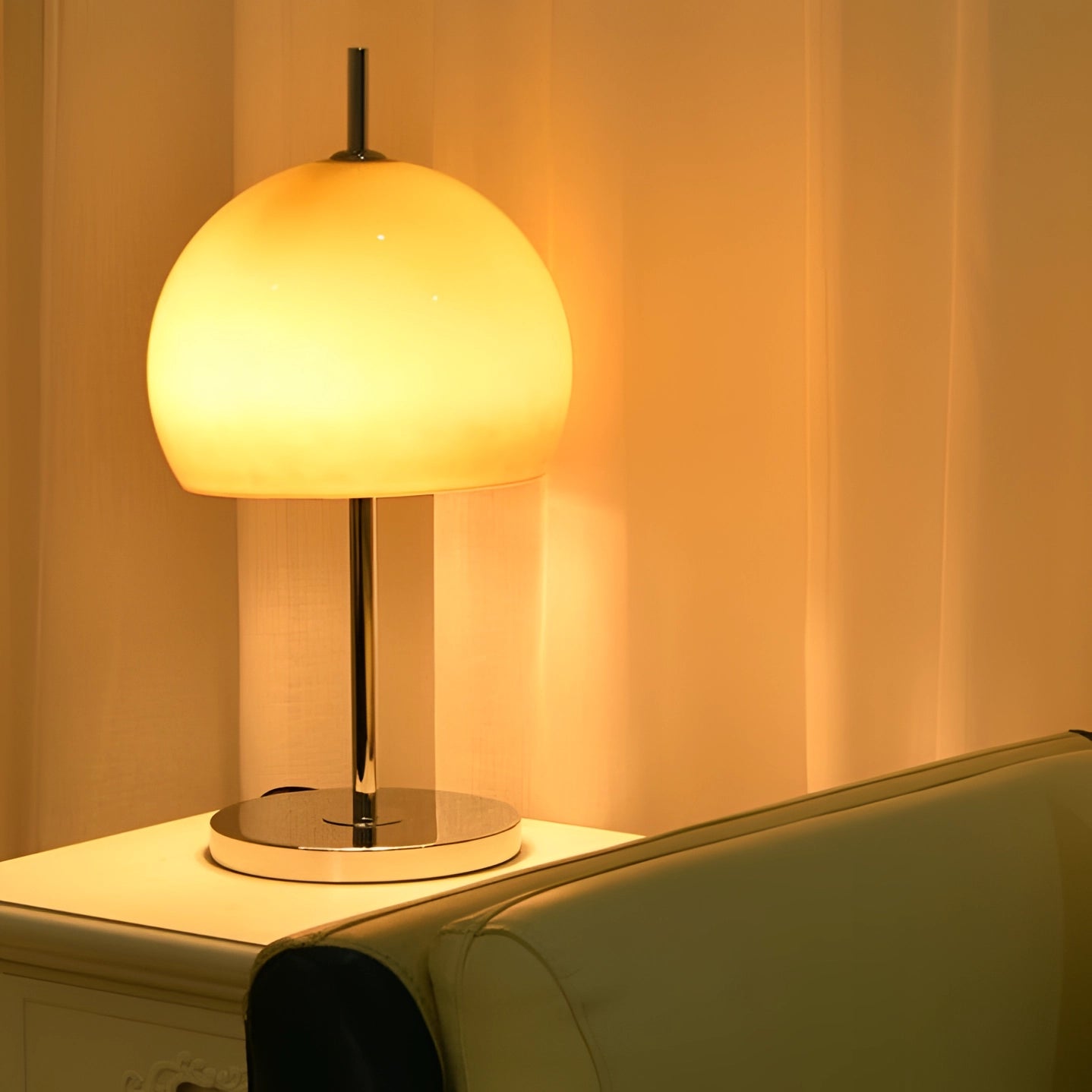 Modern orange globe table lamp with chrome base and warm light on a wooden table.
