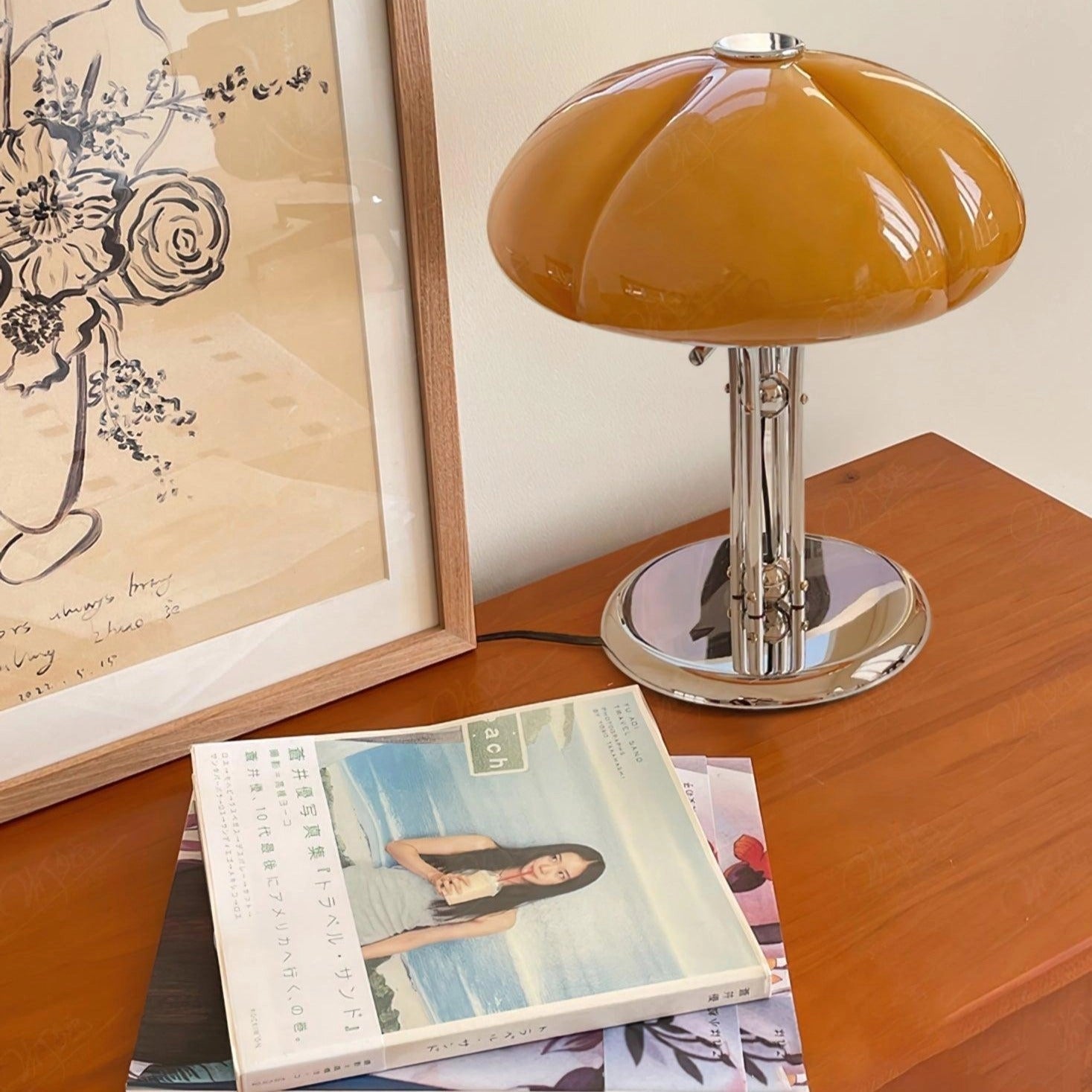 Modern orange globe table lamp with chrome base emitting warm light, placed on a wooden surface.