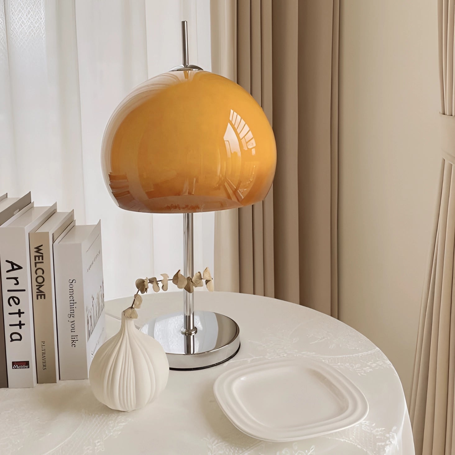 Modern orange globe table lamp with chrome base emitting warm light, placed on a wooden table in a stylish interior design setting.