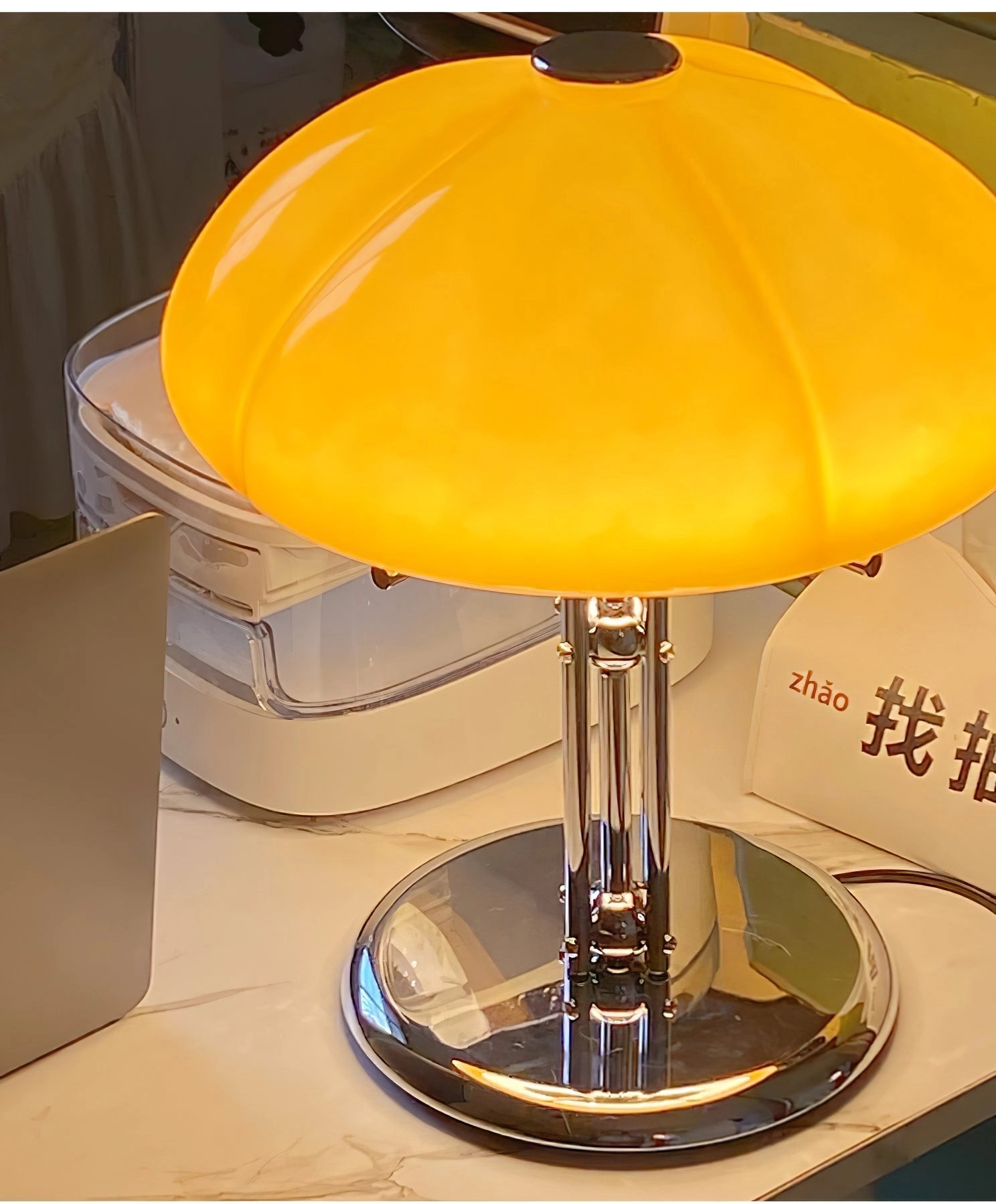 Modern orange globe table lamp with a chrome base, featuring warm amber light and a decorative glass lampshade.