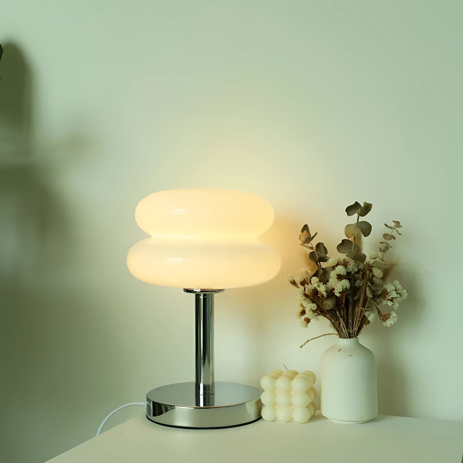 Modern orange spiral table lamp with a sleek designer LED, featuring a stylish base, placed on a wooden table in a room setting. The lamp is surrounded by decorative elements, including a small plant and a neutral-toned background that enhances its vibrant color.