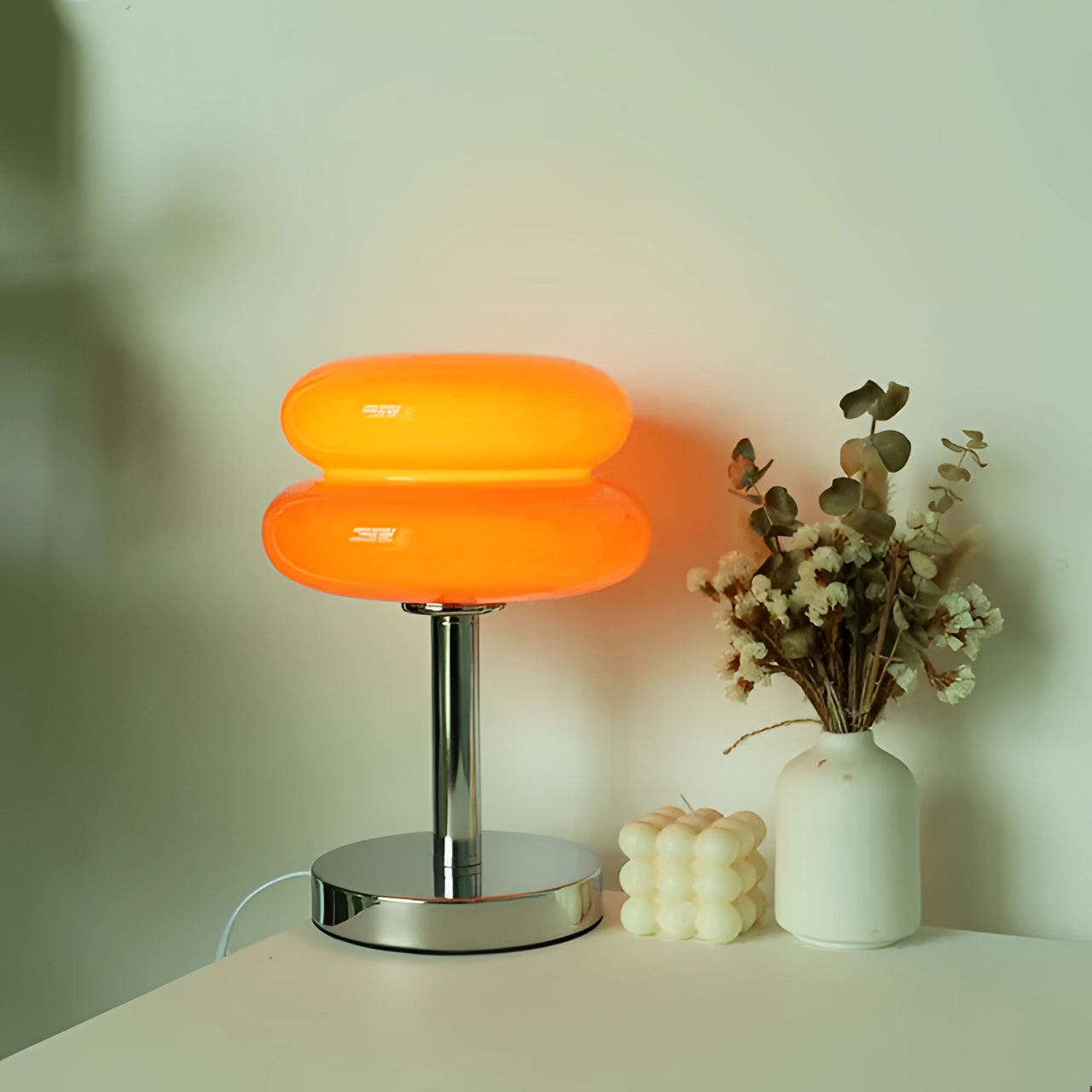 Modern dark orange spiral table lamp with a stylish base, featuring a designer LED light. The lamp is positioned on a wooden coffee table, with a USB port option visible. The setting includes elements like a vase and a flowerpot, complementing the warm tones of the orange lamp.