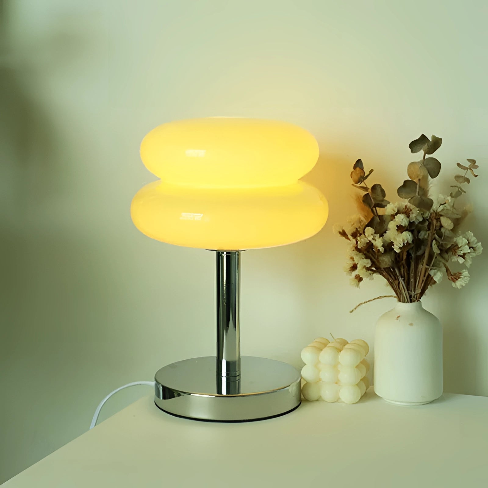 Modern orange spiral table lamp with a stylish base, featuring a unique LED design, placed on a table next to a plant in a vase. The lamp has a peach-colored lampshade that complements the overall aesthetic.
