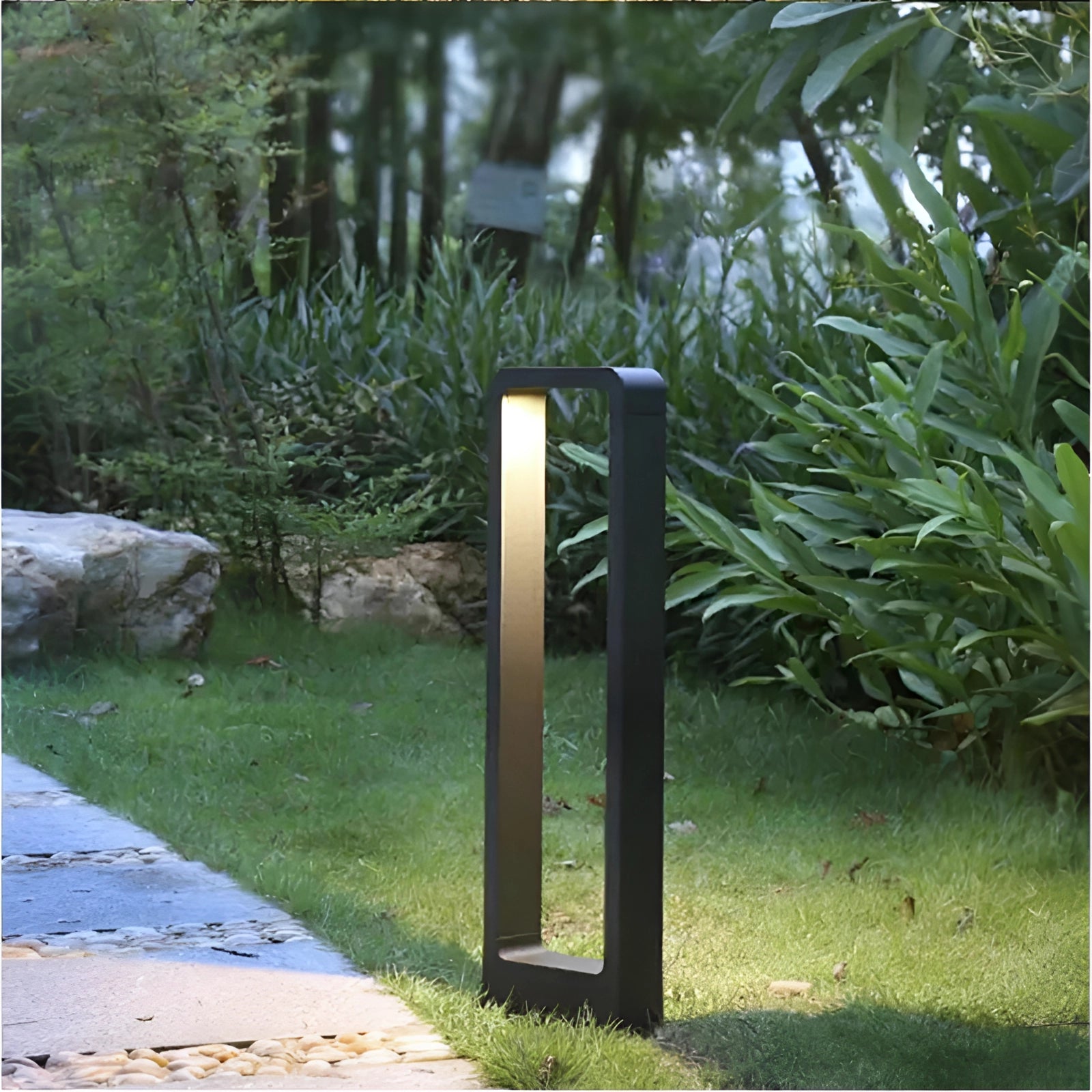 Modern outdoor LED pathway lights illuminating a garden pathway surrounded by lush greenery and shrubs, with a sleek weatherproof aluminum lamp design.