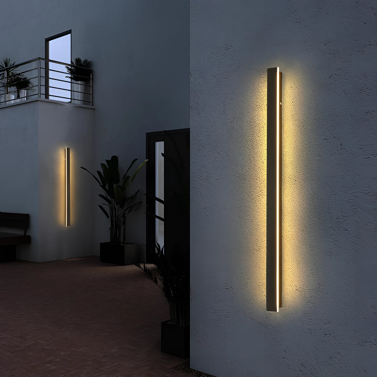 Modern outdoor LED wall light with a slim, minimalist design mounted on a wooden facade, surrounded by potted houseplants.