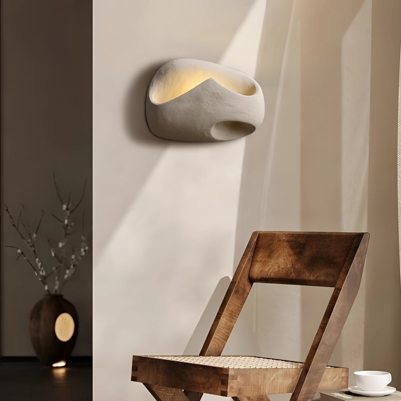 Modern pebble wall lamp with a stone look design, mounted on a wooden panel, creating a natural and artistic ambiance indoors.