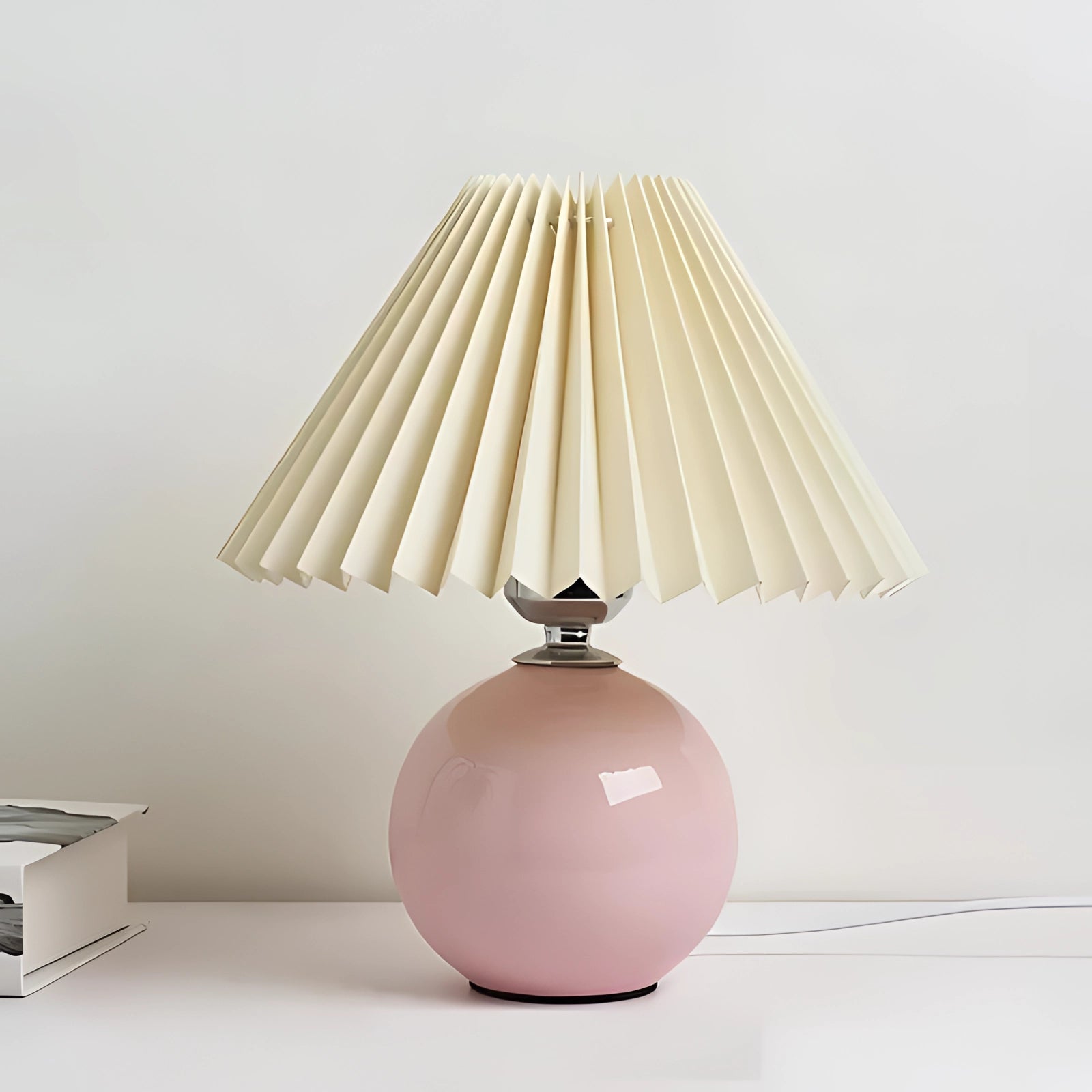 Modern pink ceramic table lamp with a pleated cream pink shade, featuring Scandinavian design elements and a wooden base.
