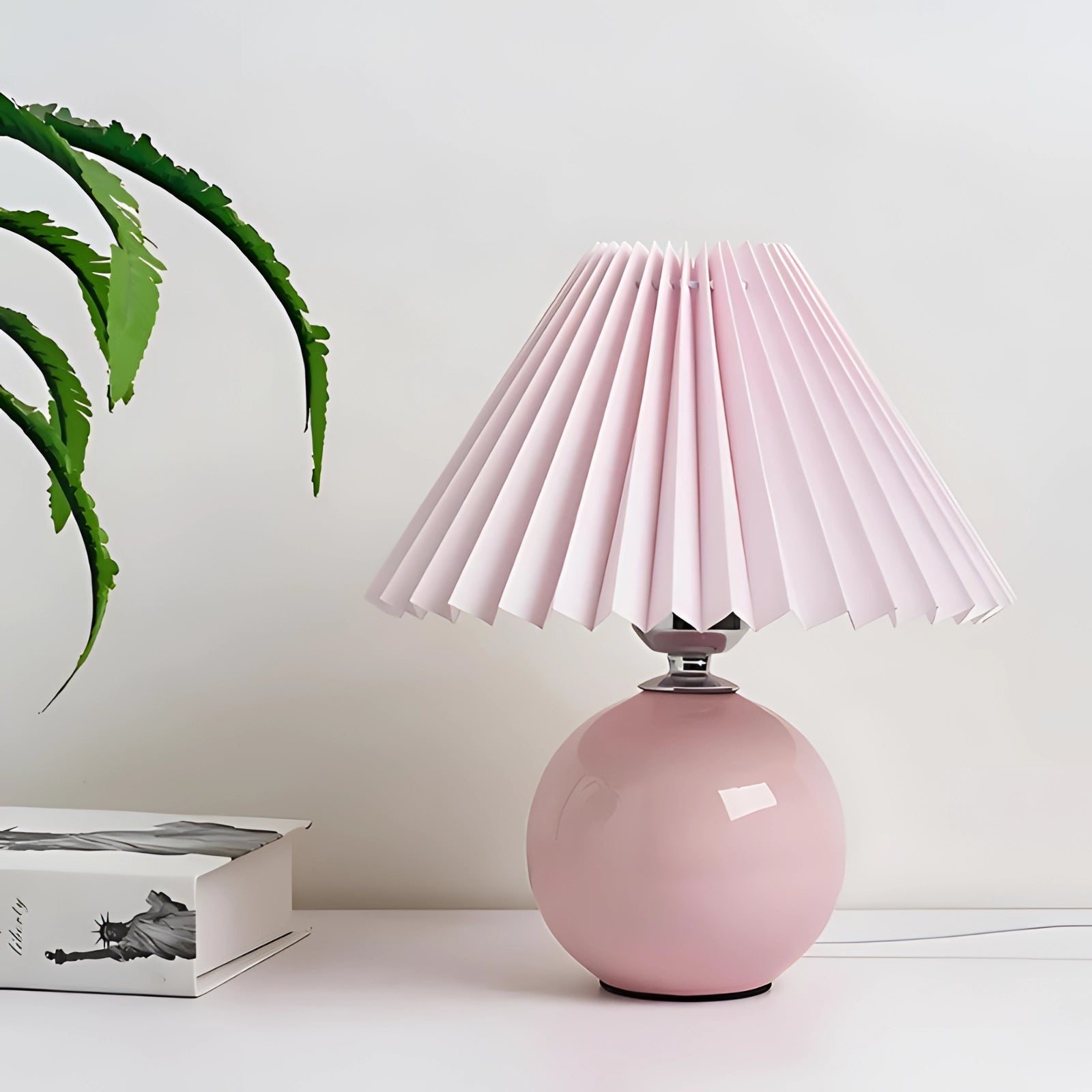 Modern light pink ceramic lamp with a pleated shade, featuring a Scandinavian design, placed in an interior setting.