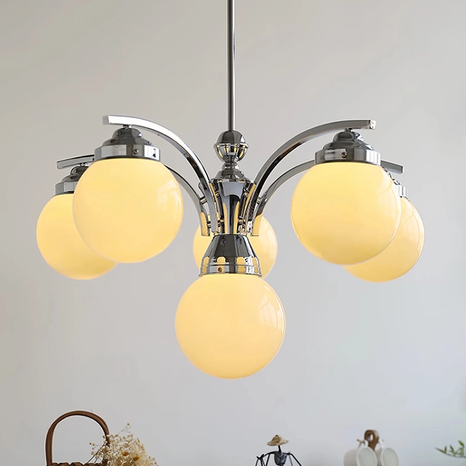Modern pink glass chandelier with minimalist design, hanging from ceiling, featuring symmetrical circular metal frame and elegant glass elements.