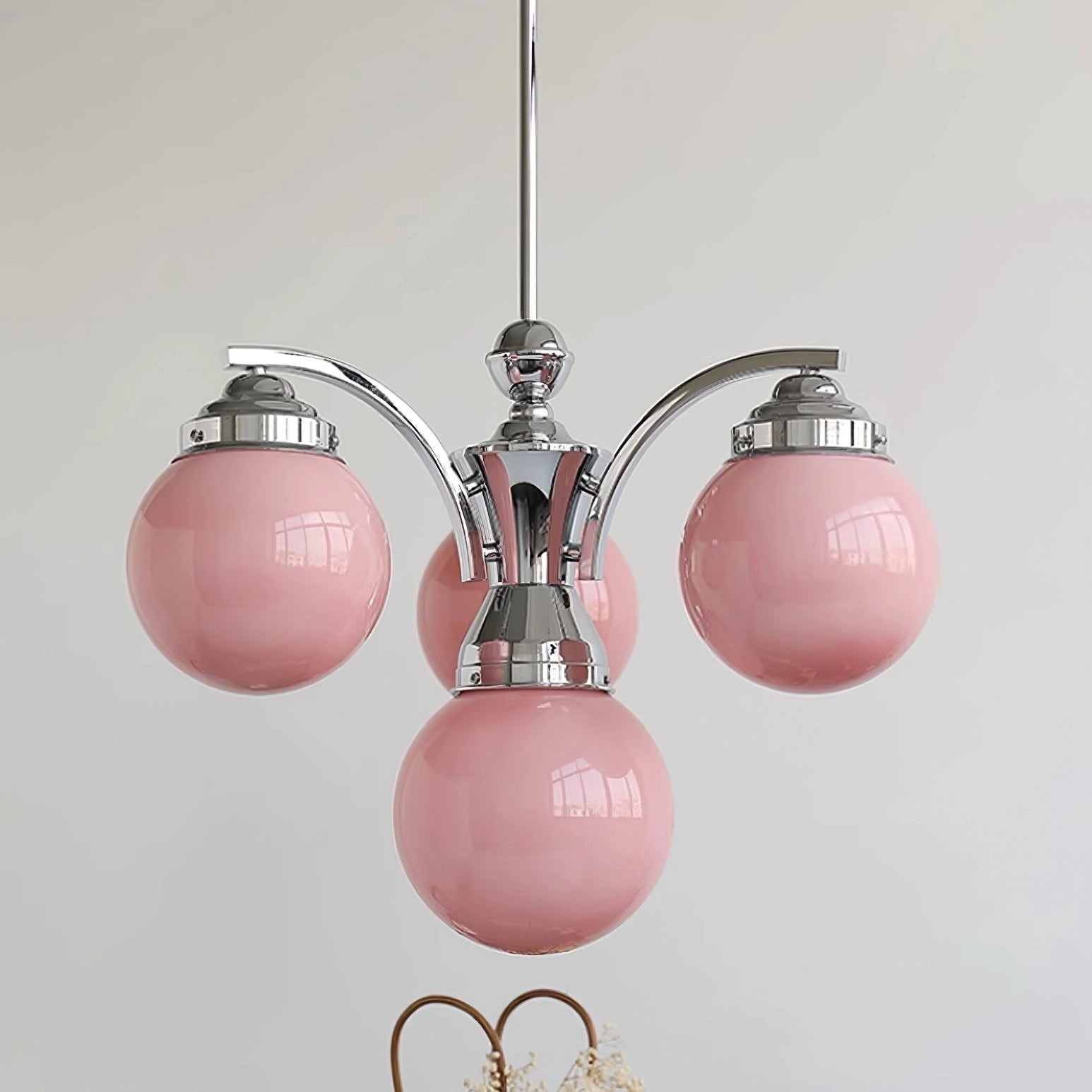 Modern pink glass chandelier with elegant minimalist design, featuring circular elements and magenta hues, hanging from the ceiling.