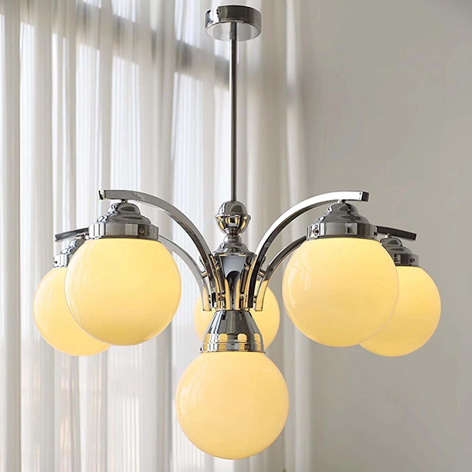 Modern pink glass chandelier with elegant minimalist design, featuring a metal ceiling fixture and a stylish shade, illuminating an interior space.