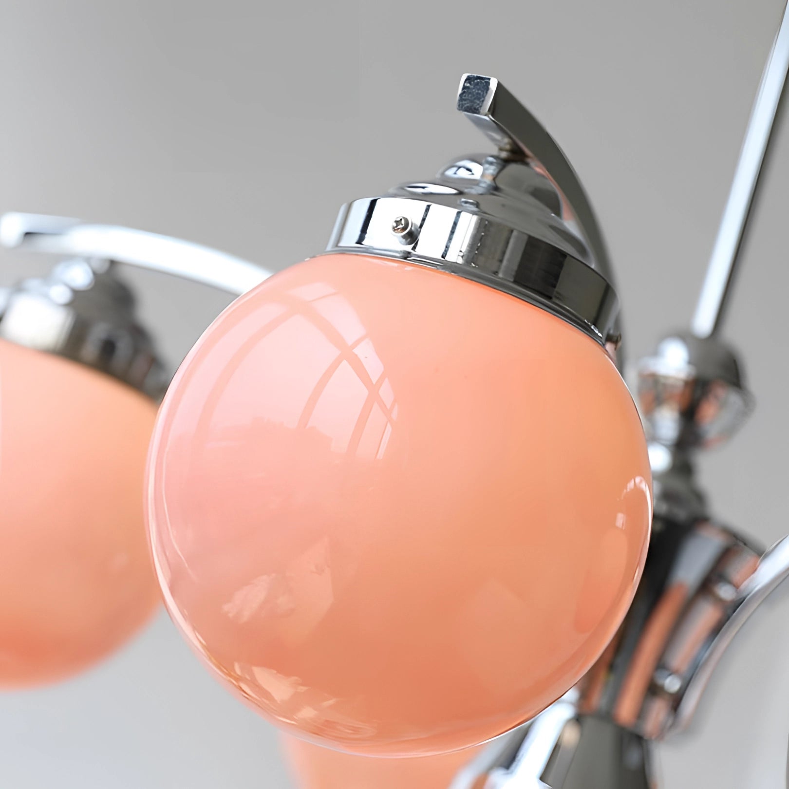 Elegant minimalist modern pink glass chandelier with circular metal accents hanging from the ceiling.
