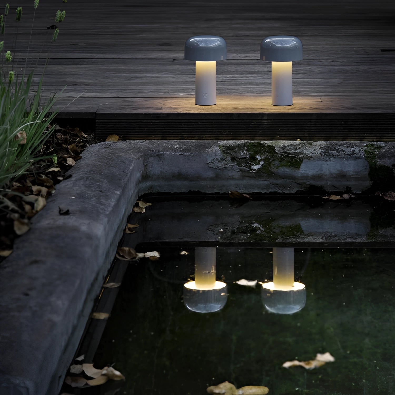 Modern portable wireless LED lamp with a sleek design and touch control, placed on a wooden surface next to a small potted plant, emitting a soft, warm glow.