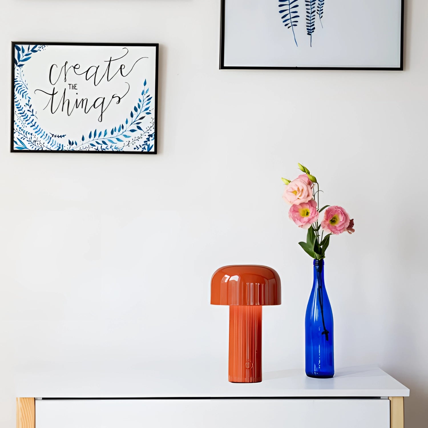 A modern portable wireless LED lamp with a sleek design and touch control, placed next to a vase of flowers on a rectangular surface.