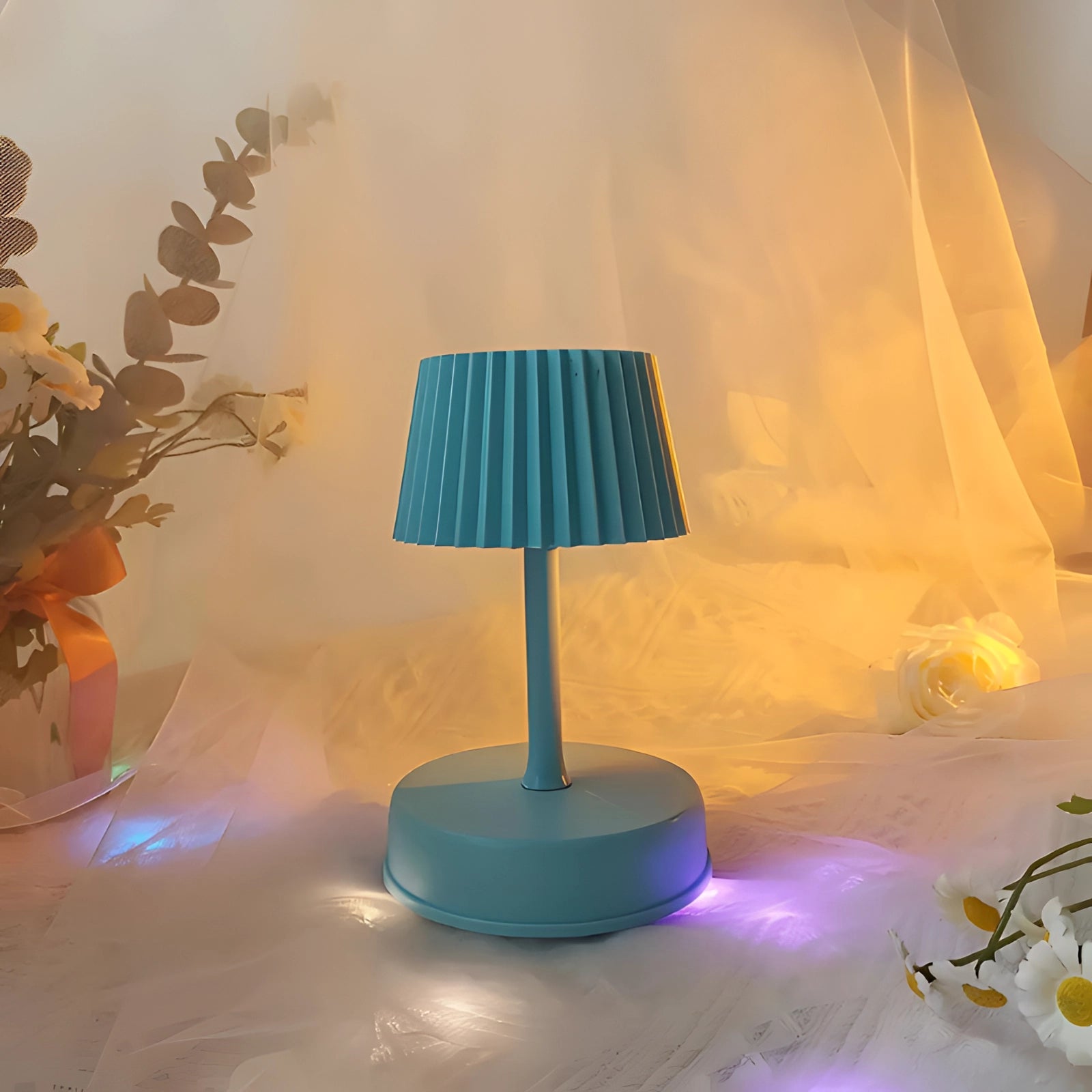 Modern red table lamp with a pleated lampshade placed on a wooden table, surrounded by stylish interior decor elements, including a chair and contemporary art pieces.