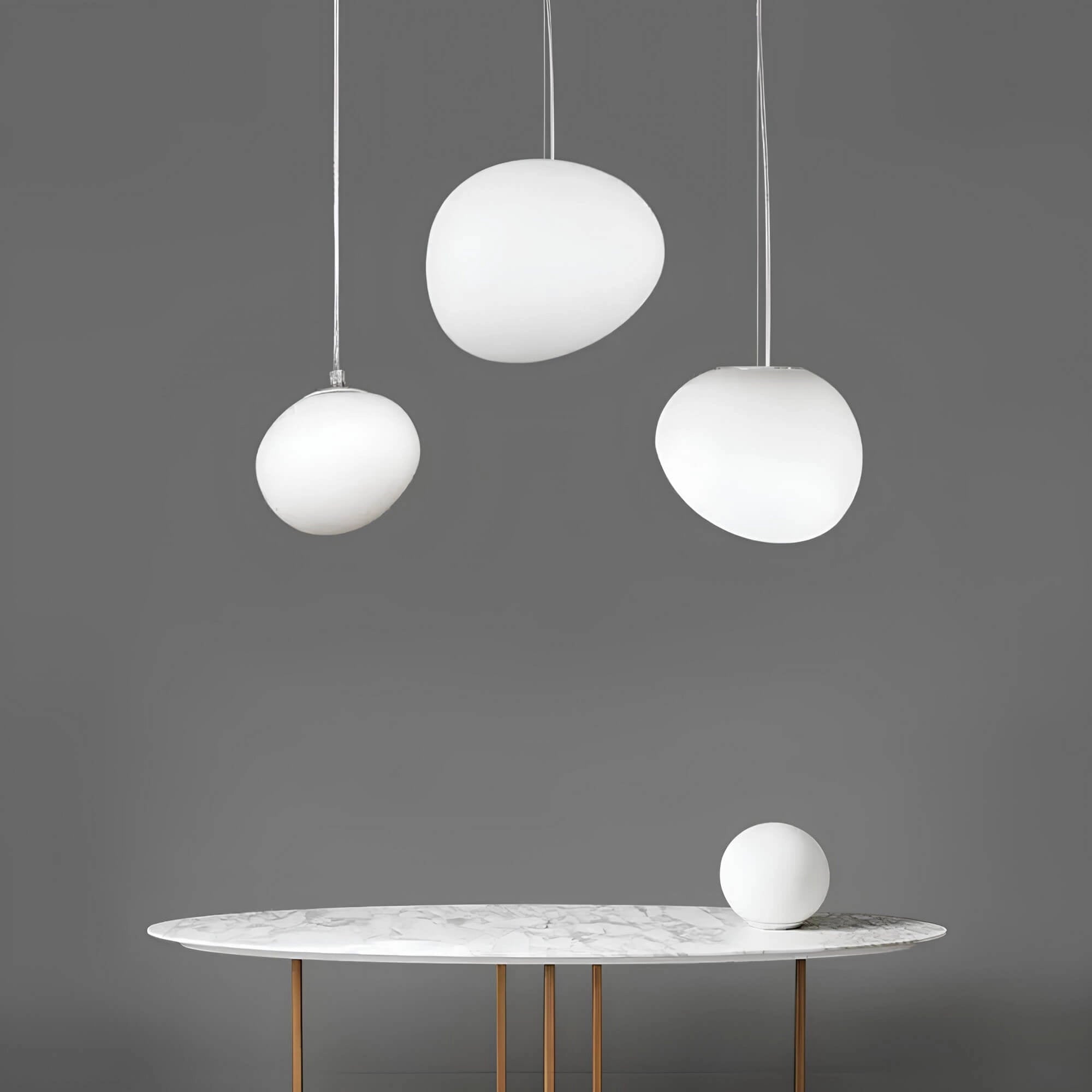 Modern round pendant light fixture with a minimalistic sphere design, featuring a black and white color scheme, hanging from the ceiling. The light is positioned above a table, complementing the contemporary architecture and interior design elements.
