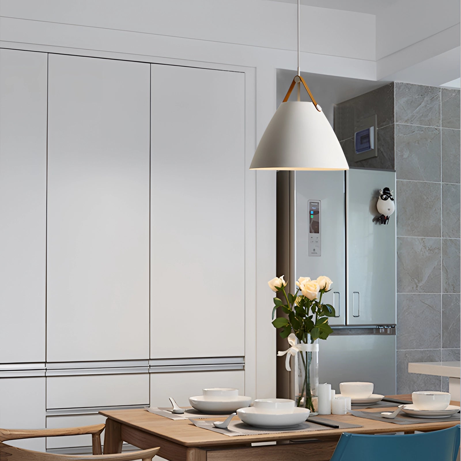 Large white modern Scandinavian pendant light hanging above a wooden table with a houseplant, showcasing interior design elements.