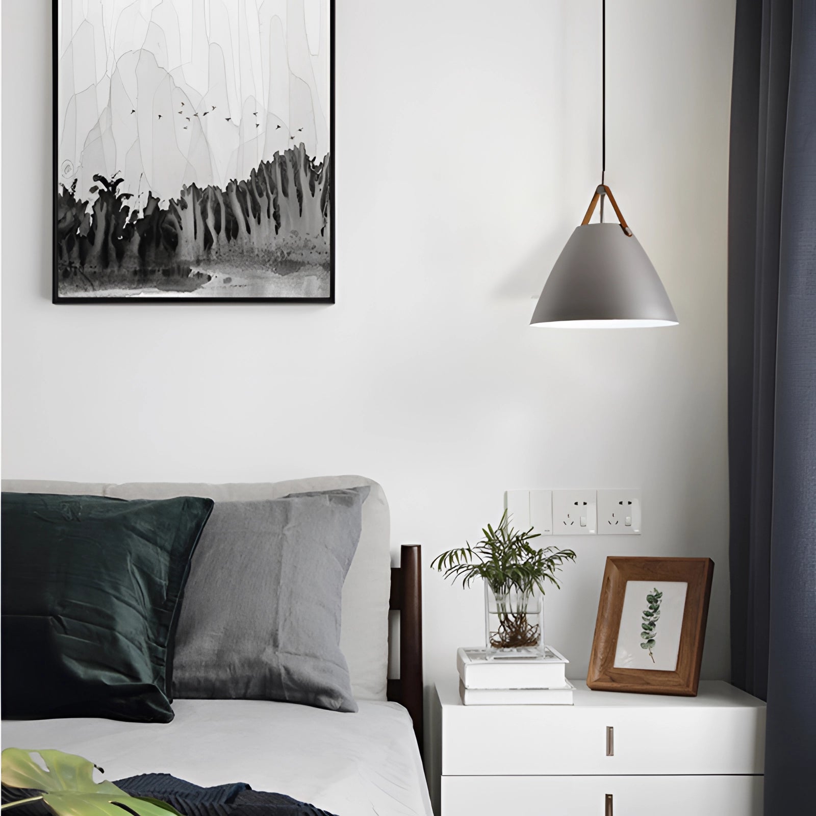 Modern Scandinavian pendant light with large adjustable black and white lampshade, hanging in a stylish interior setting featuring minimalist furniture, a wooden picture frame, and a plant, embodying contemporary and comfortable design elements.