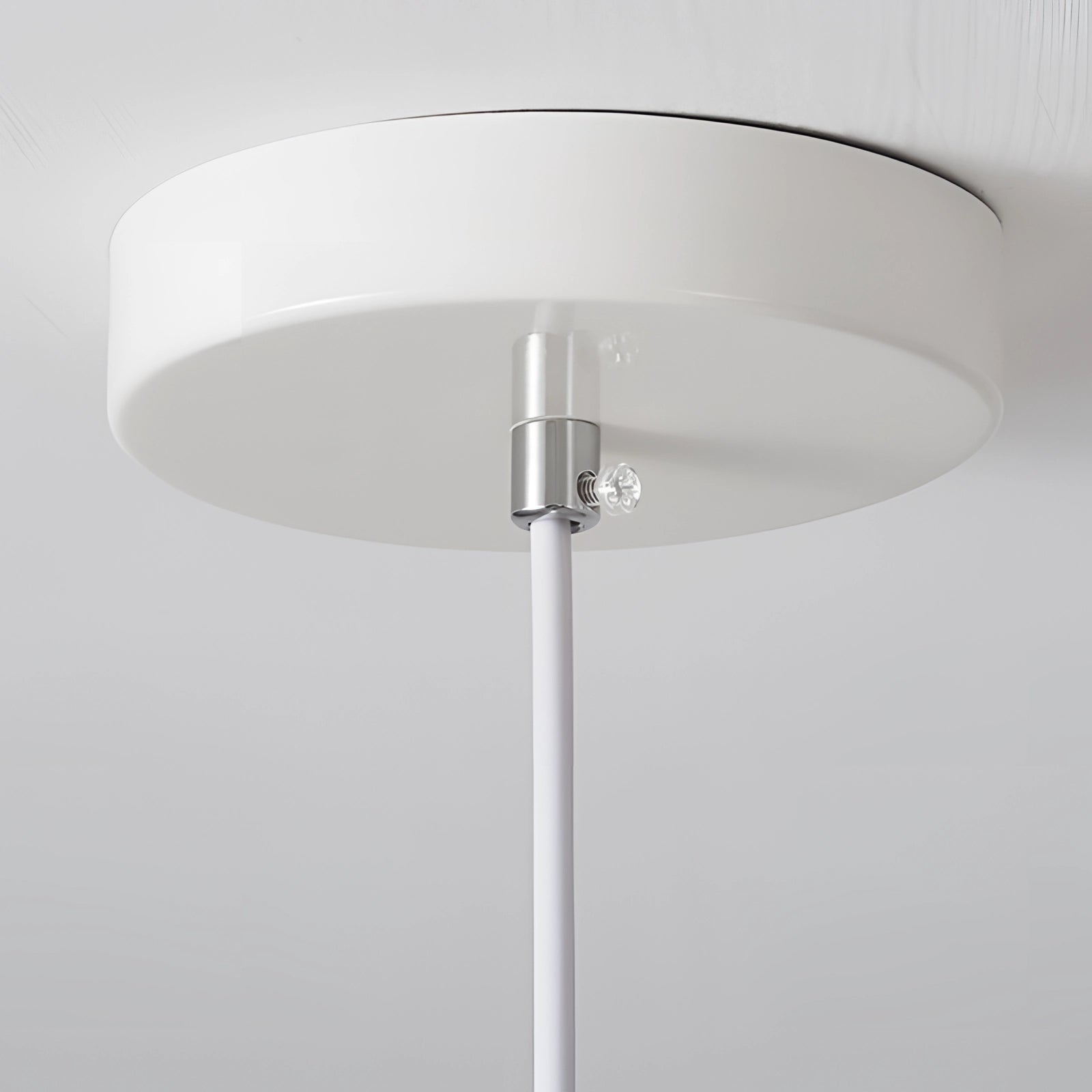 Modern Scandinavian white LED pendant light fixture with a minimalist design, featuring a sleek glass shade and suspended from the ceiling, casting a soft glow onto a table surface below.