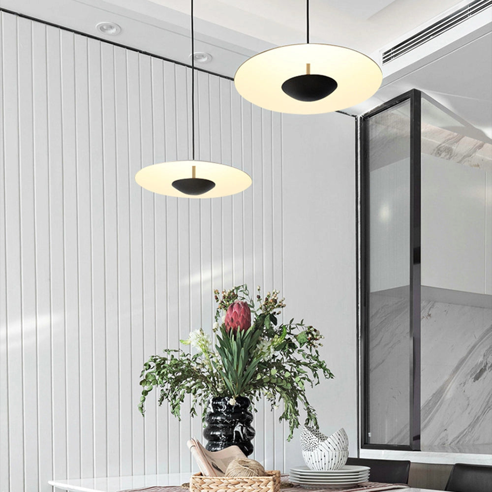 Modern Scandinavian wooden and metal pendant light hanging in a stylish dining room with white walls, featuring a houseplant in a vase on a wooden table.