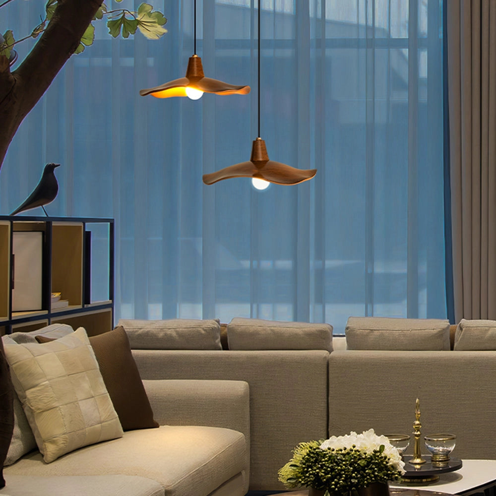 Modern sculptural wood pendant light with an organic design, featuring a 14.9-inch size and two-light configuration, hanging in a stylish interior setting with furniture, plants, and a large window.
