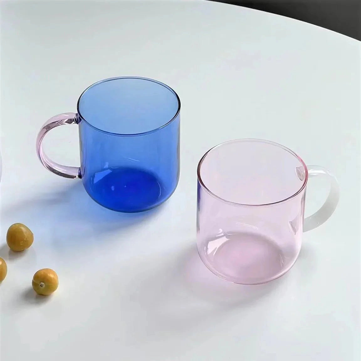 Modern smoke glass mug with a stylish grey tint, made of borosilicate glass, filled with liquid, sitting on a table.