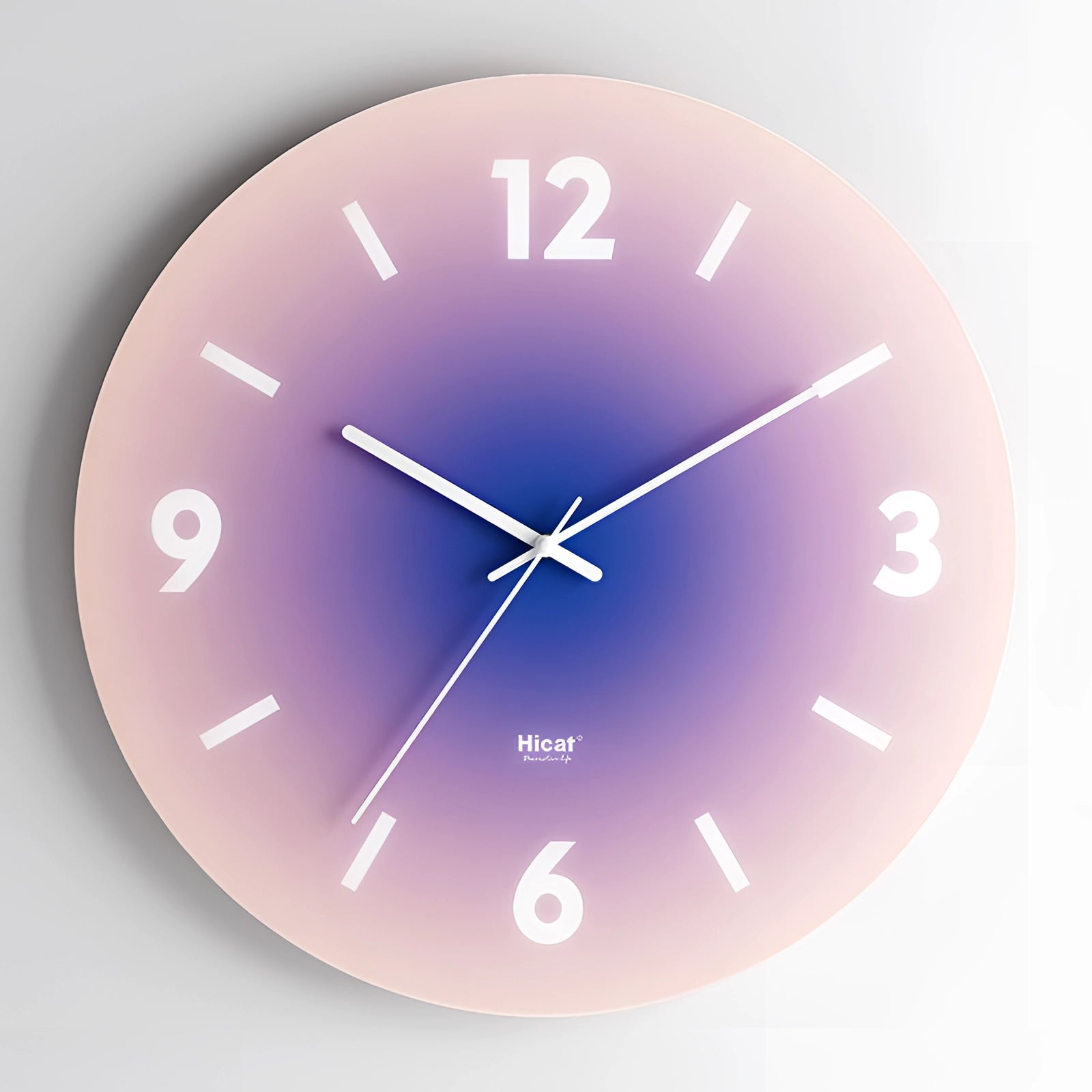 Modern wall clock with a minimalist design featuring a gradient of sunset orange to purple, displaying bold numbers on its circular face.