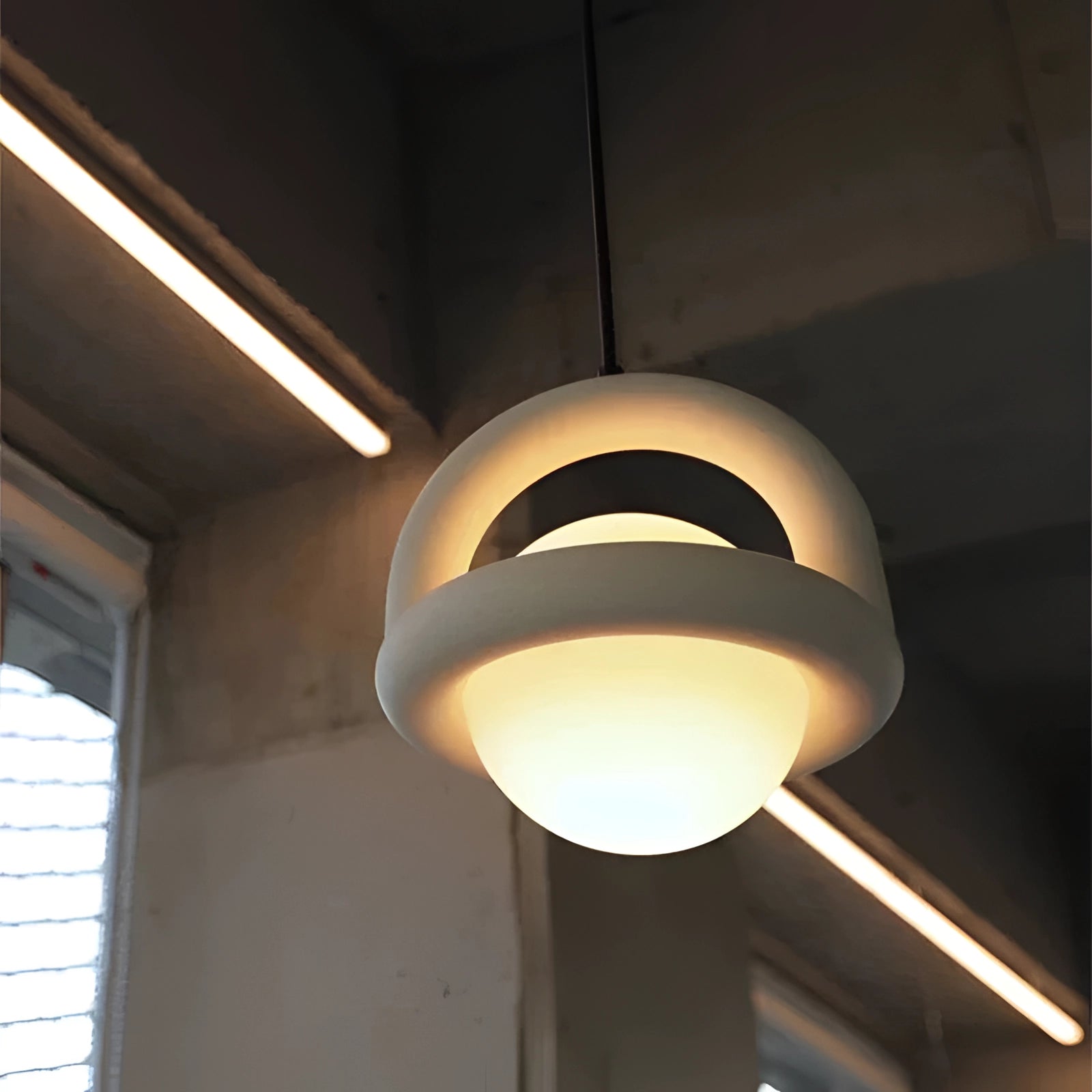 Modern teal orb pendant light with a Scandinavian mid-century style, featuring a circular design and suspended from the ceiling, enhancing the room with its sleek and symmetrical aesthetic.
