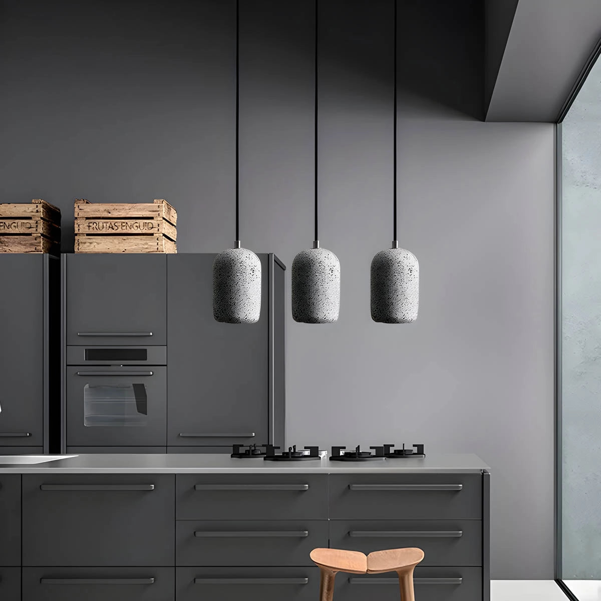 Modern concrete pendant lights hanging over a sleek kitchen design with wooden cabinetry and a minimalist interior.