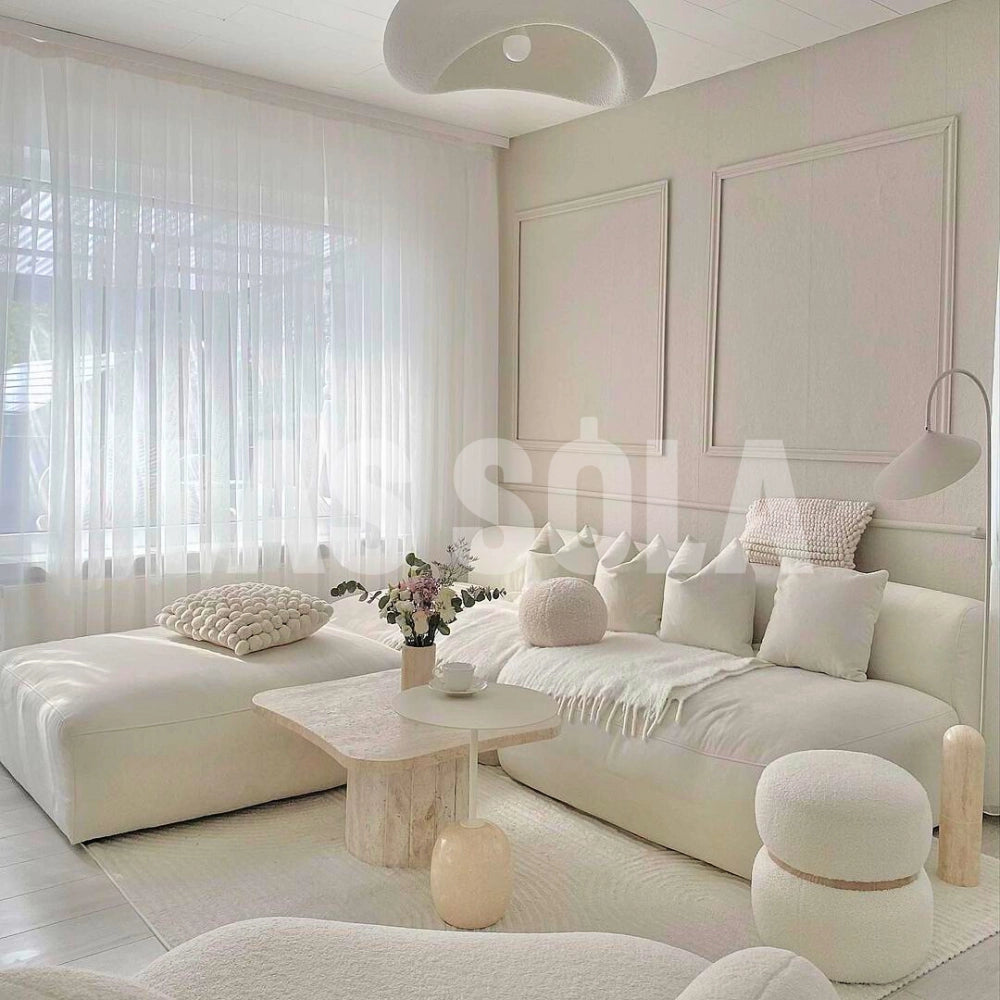 A modern textured pendant light with a minimalist pebble design, featuring a stone finish, hanging in a stylish living room setting with a comfortable couch, pillows, and a table.
