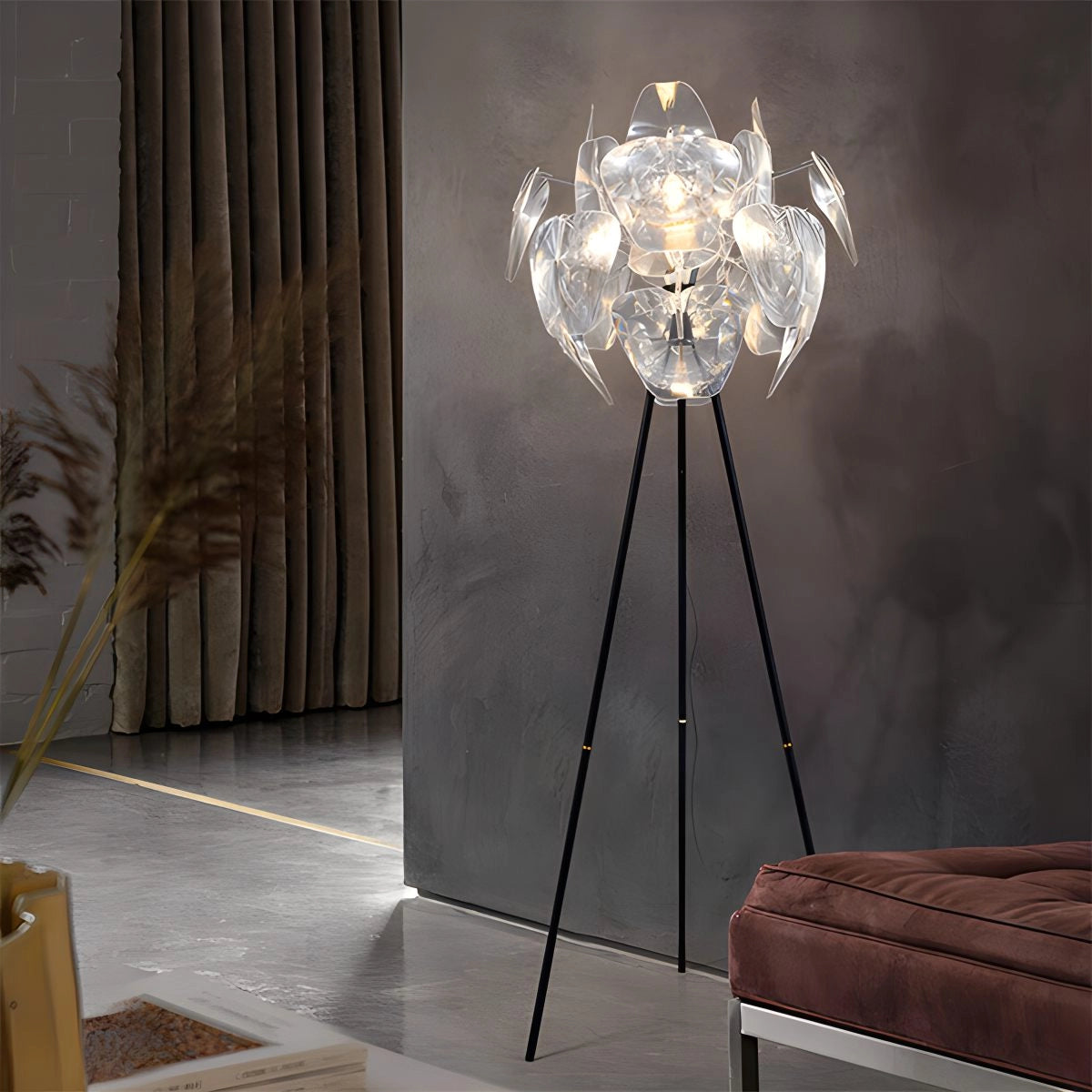 Modern tri-leg floor lamp with a petal design, featuring a clear acrylic globe, standing on wooden legs in a stylish interior setting.
