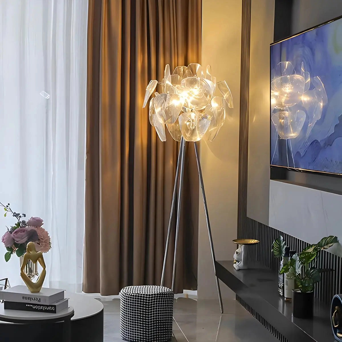 Modern tri-leg floor lamp with petal design and clear acrylic globe, placed in a stylishly decorated room with a table, plant, and wooden elements.