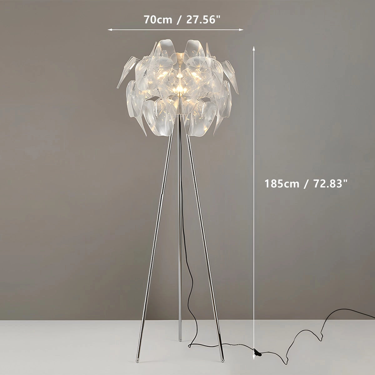 Modern tri-leg floor lamp with petal design featuring a clear acrylic globe, positioned next to a plant.