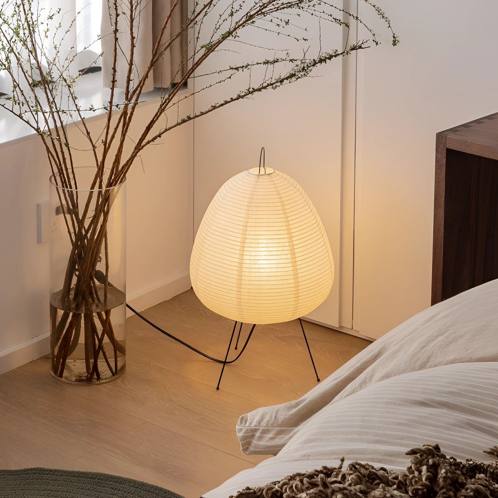 Modern tripod floor lamp with a Japanese-inspired design, featuring a wooden base and a soft ambient light shade, named Noguchi, ideal for interior design and adding comfort to living spaces.