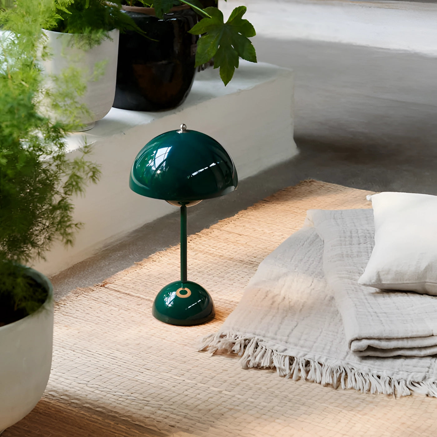 Modern white mushroom lamp on a wooden table next to a potted houseplant in a bright room with hardwood flooring and a large window.