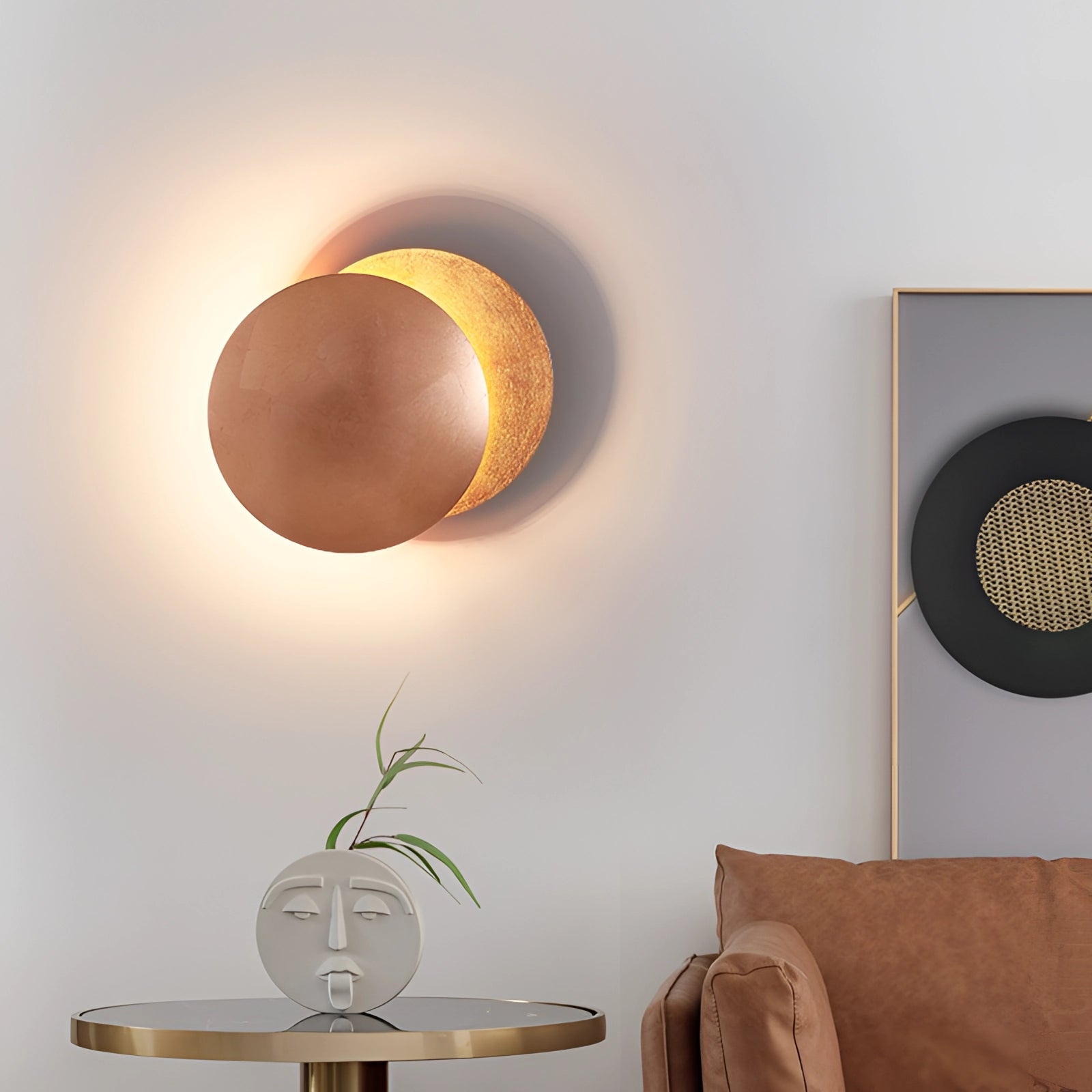 Luxury gold moon-phase wall light illuminating a modern interior space with a wooden couch, green plant, and stylish decor elements.
